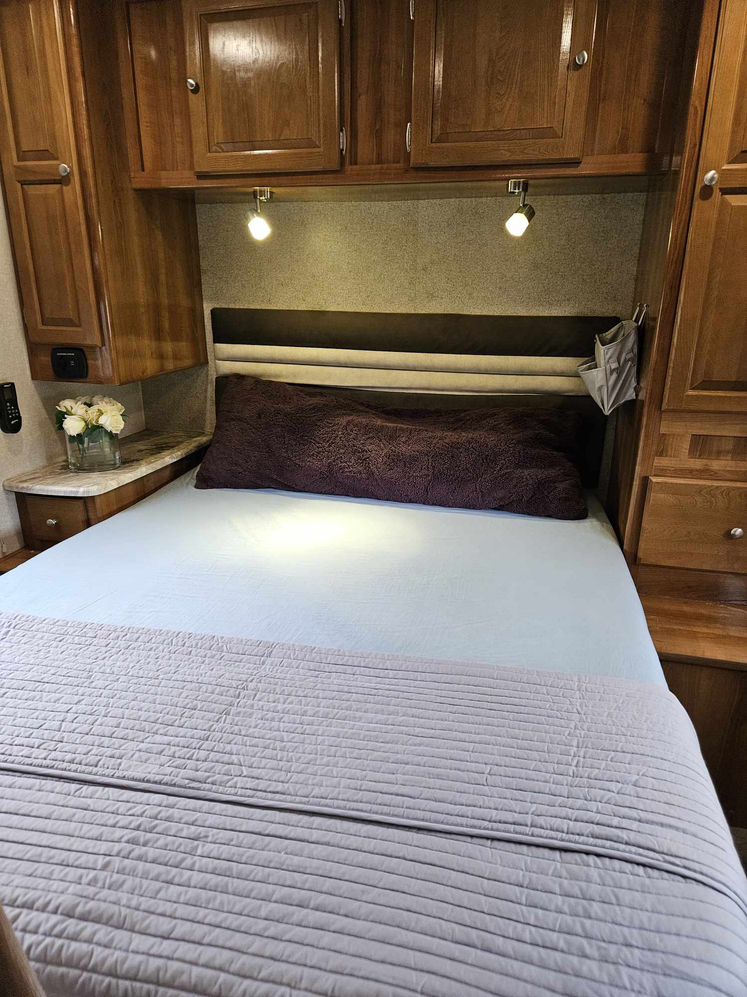 Compact RV rental bedroom featuring a comfortable bed, overhead cabinets, and soft lighting for cozy nights.. Coachmen Leprechaun 2020