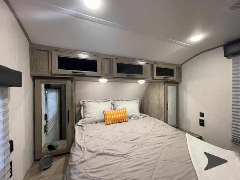 Cozy RV rental bedroom with queen bed, overhead cabinets, and mirrored closet. Perfect for comfortable travel.. Forest River Cherokee Alpha Wolf 2022