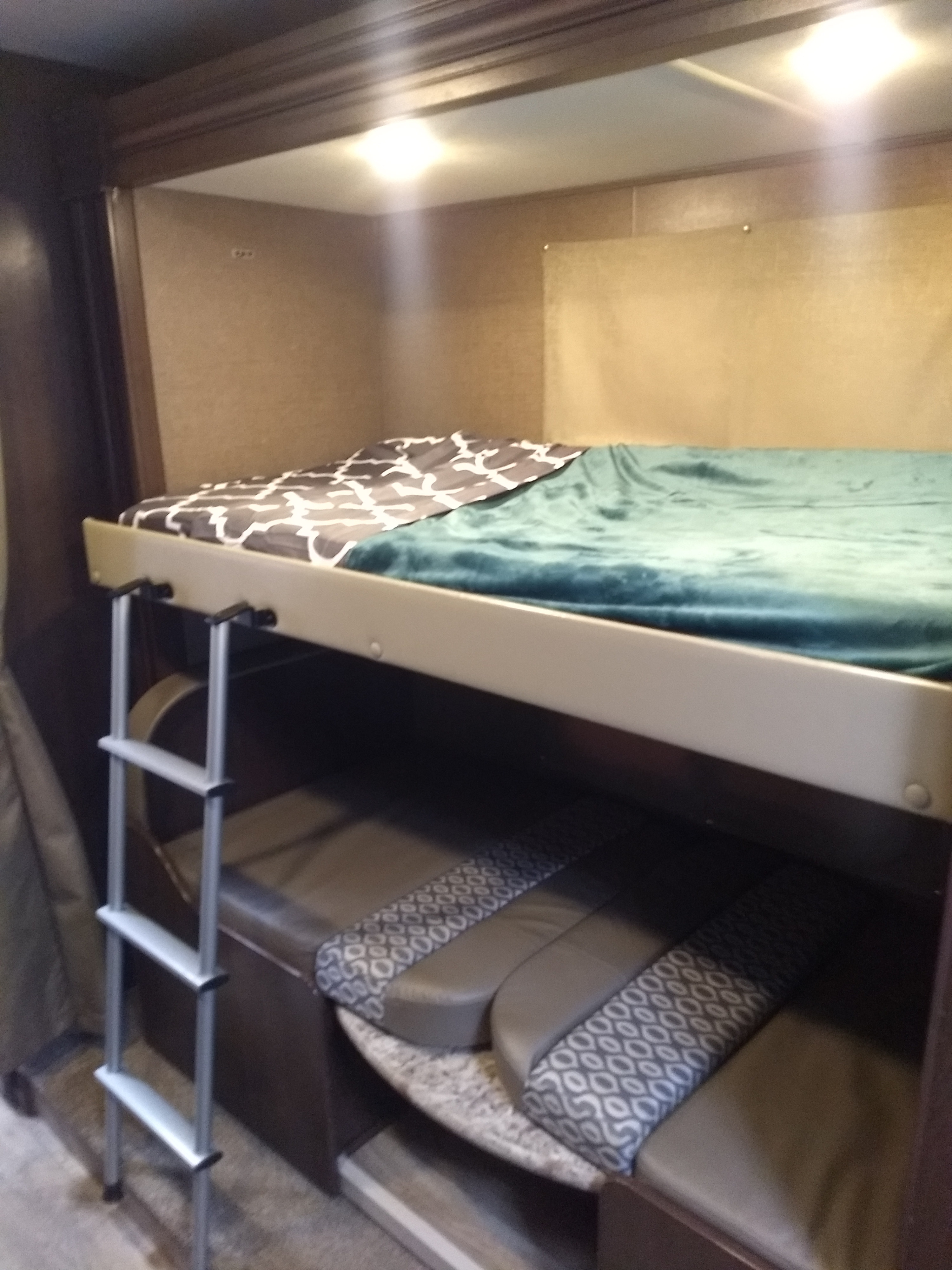 Cozy RV rental bunkhouse: upper bed with blankets, ladder access, and lower seating. Perfect for families.. Thor Motor Coach Freedom Elite 2019