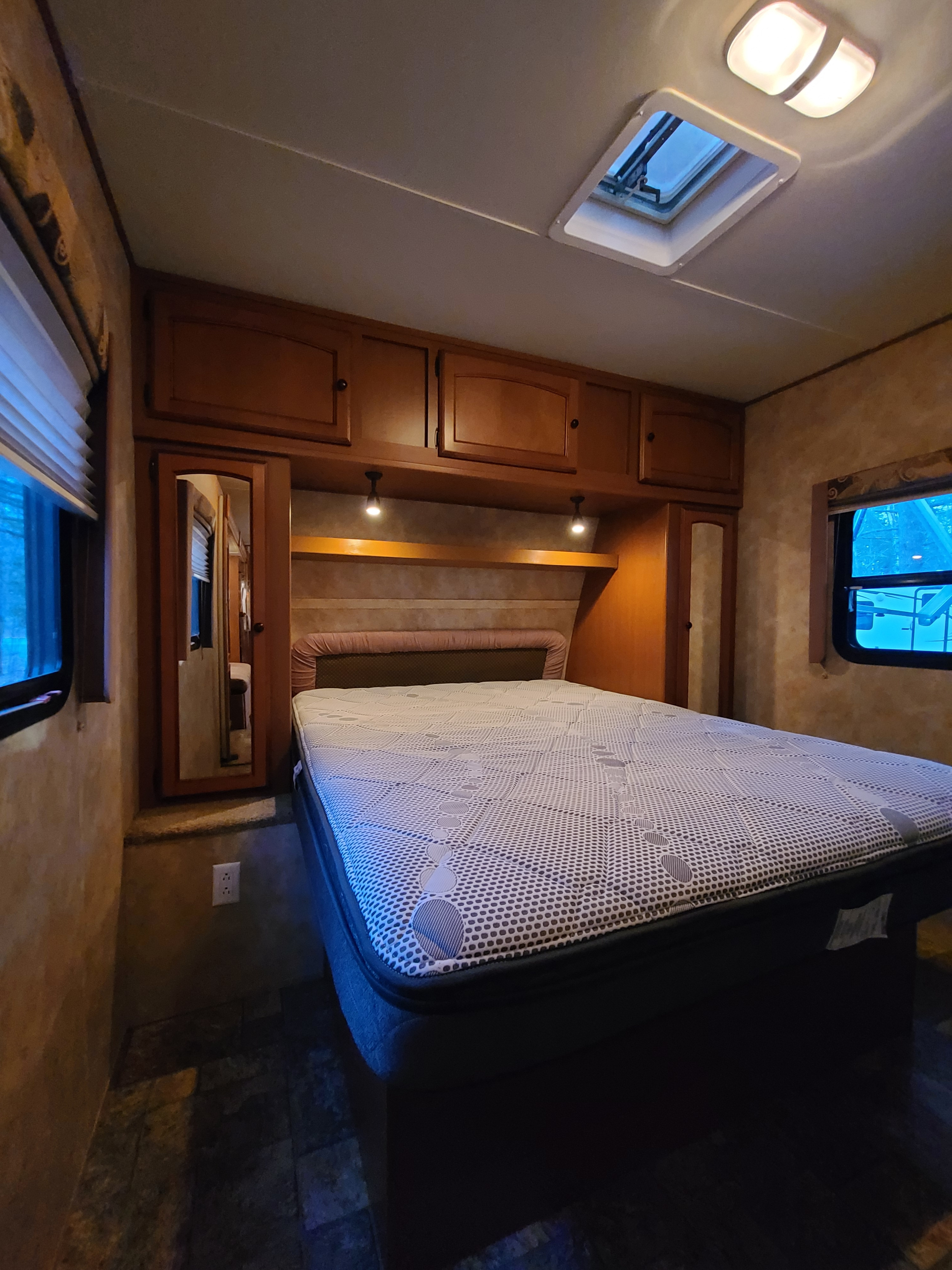 Cozy RV rental bedroom with a comfortable bed, overhead cabinets, and skylight.. Gulf Stream Gulf Breeze 2010