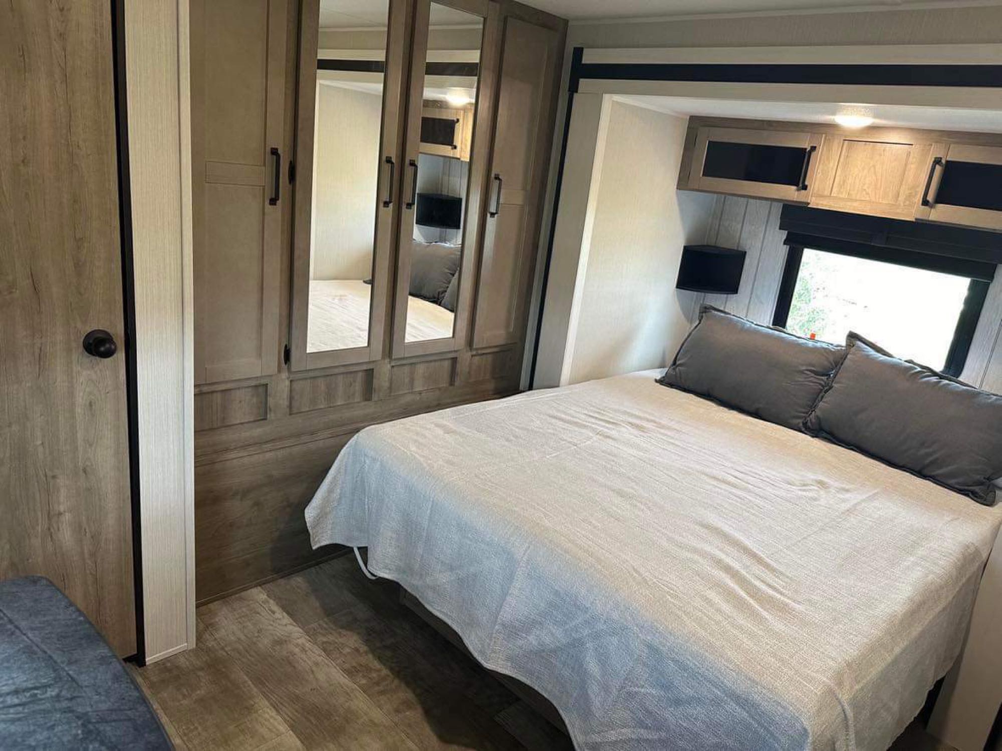 Cozy RV rental bedroom with a comfortable bed, mirrored wardrobe, and overhead storage. Ideal for your next trip.. Forest River Palomino Puma 2024
