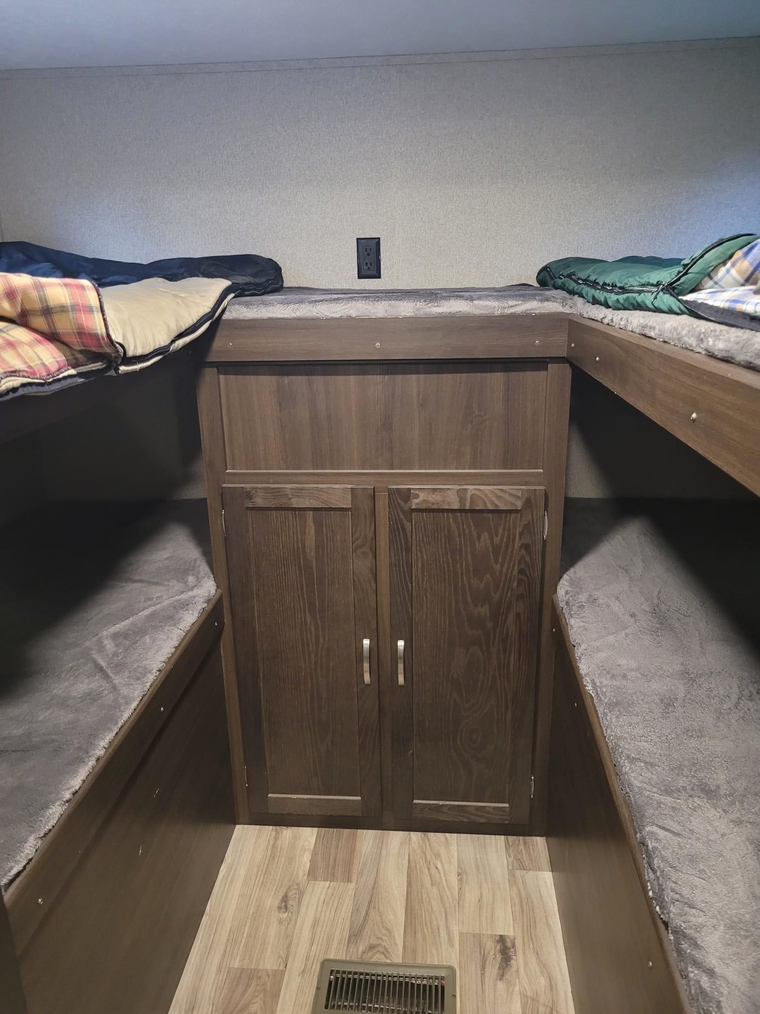 An RV rental's sleeping area features four bunk beds, two upper and two lower, centered around a wood storage cabinet.. Keystone RV Springdale 2020