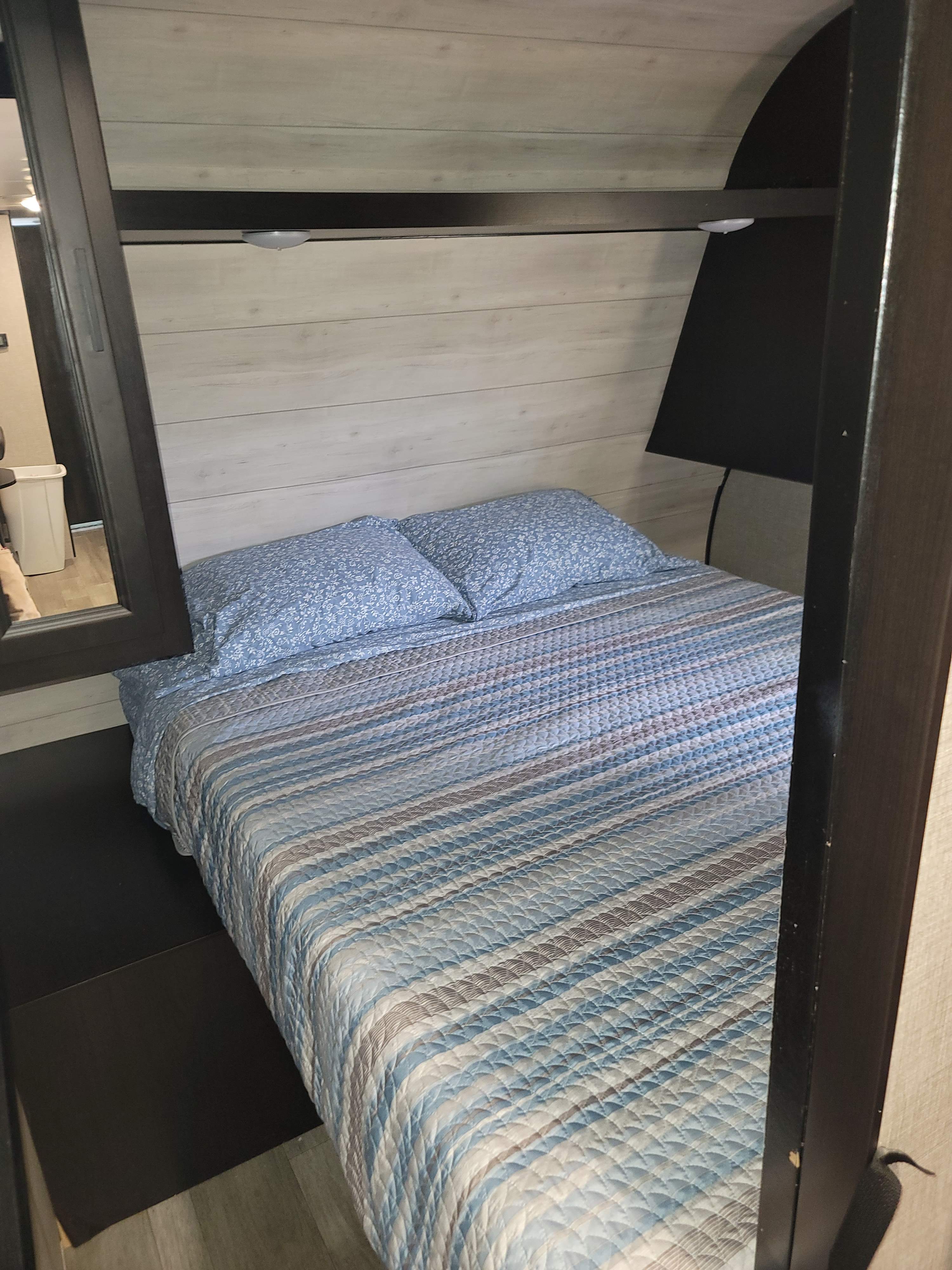 RV rental bedroom showcasing a bed with blue floral pillows, a striped quilt, and an overhead shelf with lights.. Jayco Jay Flight SLX 2022