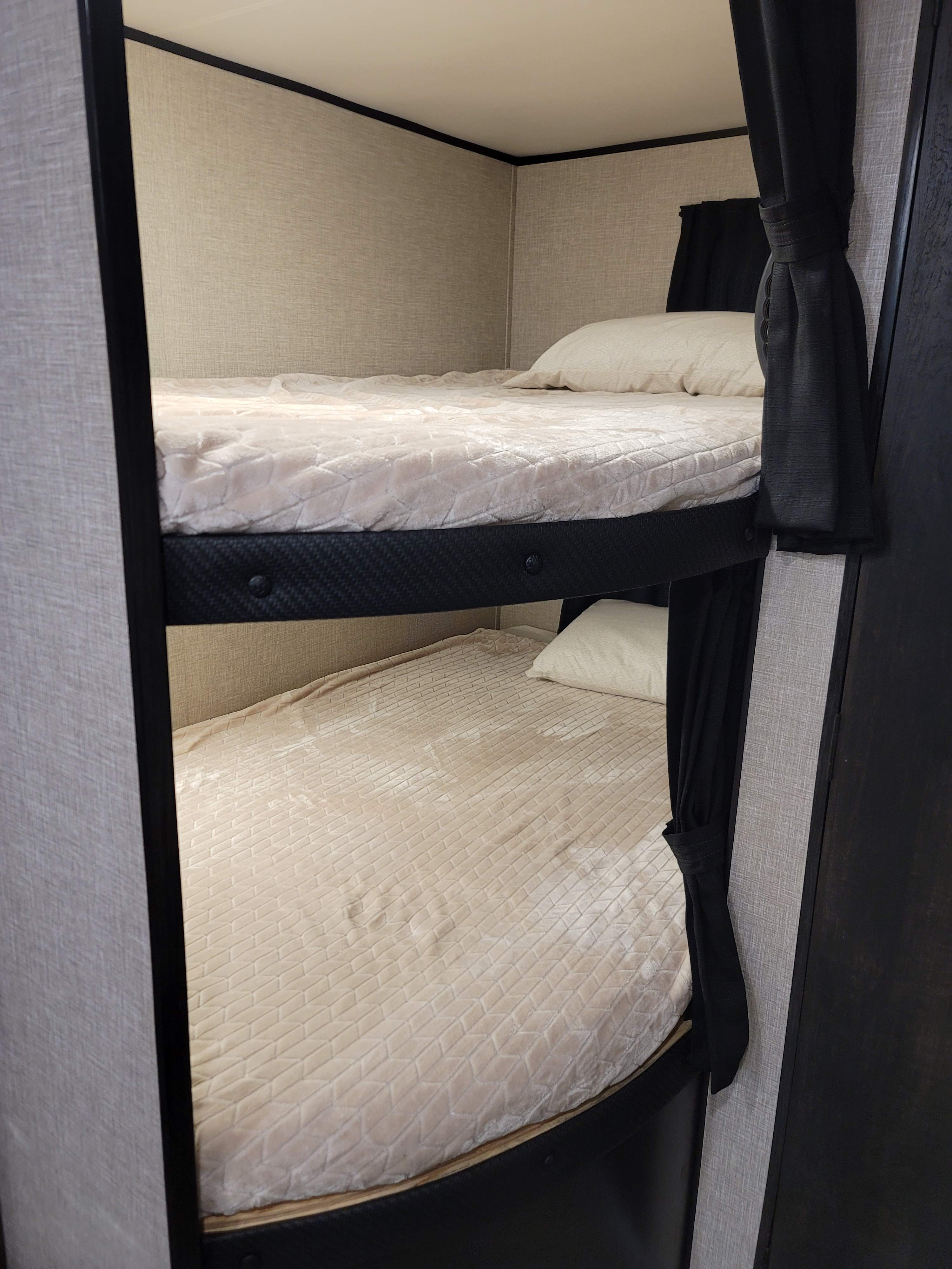 Cozy RV rental bunk beds featuring soft, light-colored bedding and dark privacy curtains, perfect for family camping.. Jayco Jay Flight SLX 2022