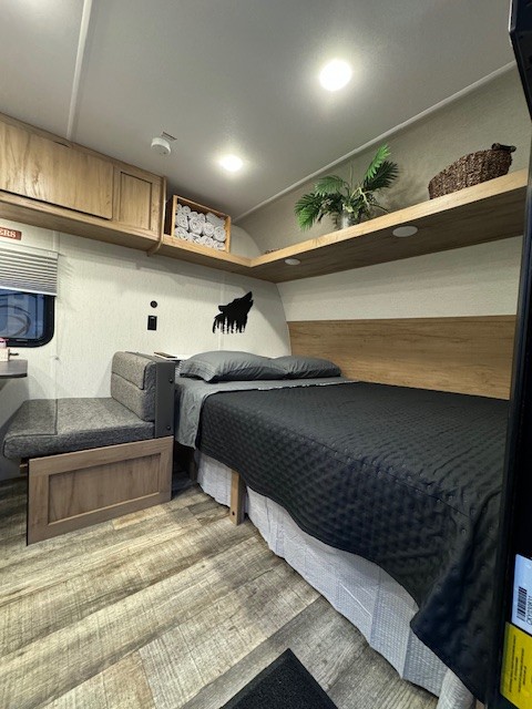 Cozy RV rental bedroom with a comfortable bed, versatile seating, and clever storage. Ideal for travel comfort.. Forest River Wolf Den 2024