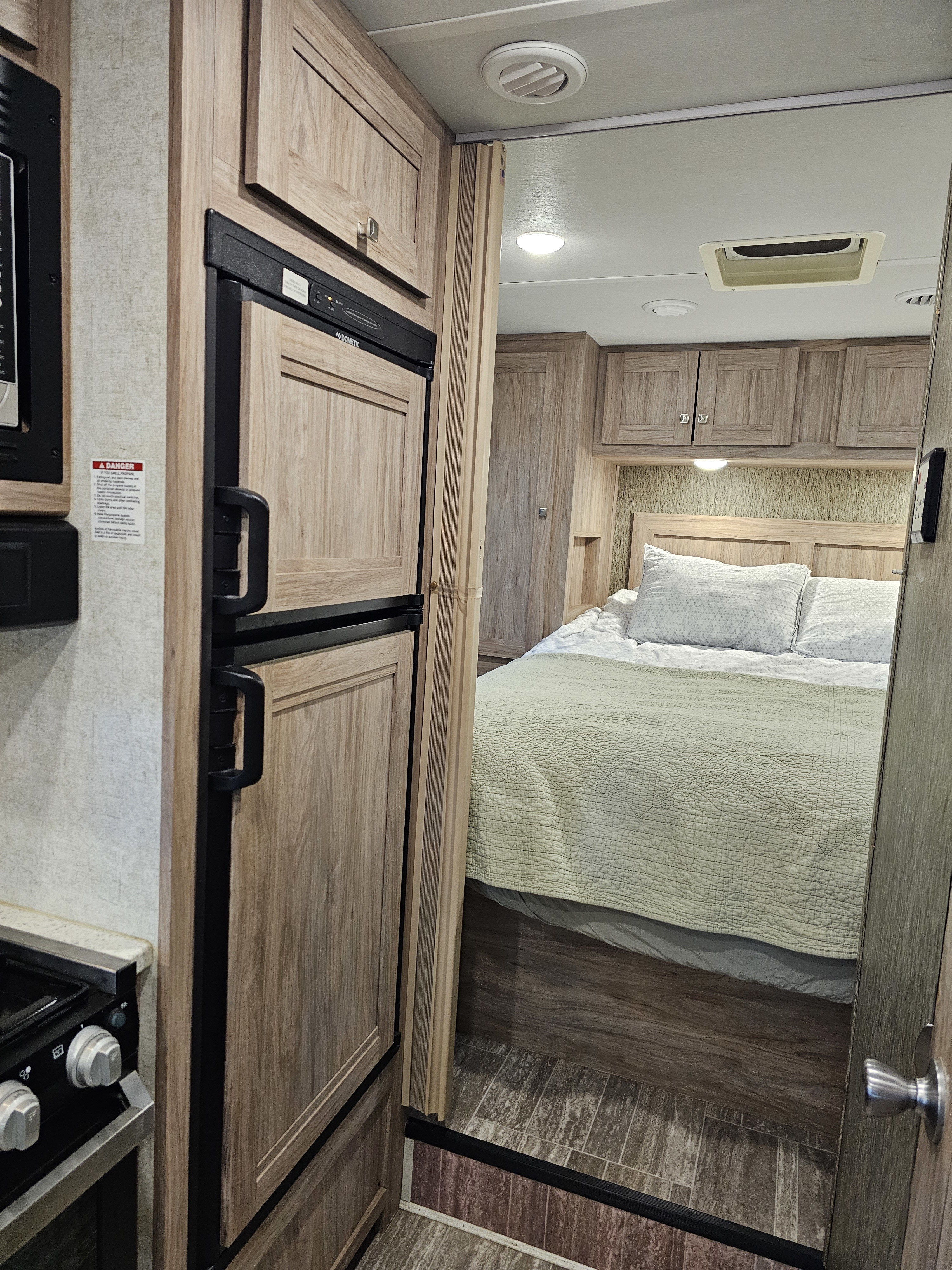 RV rental interior showcases a compact kitchen with stove and fridge, leading to a comfortable bedroom area.. Forest River Sunseeker 2019