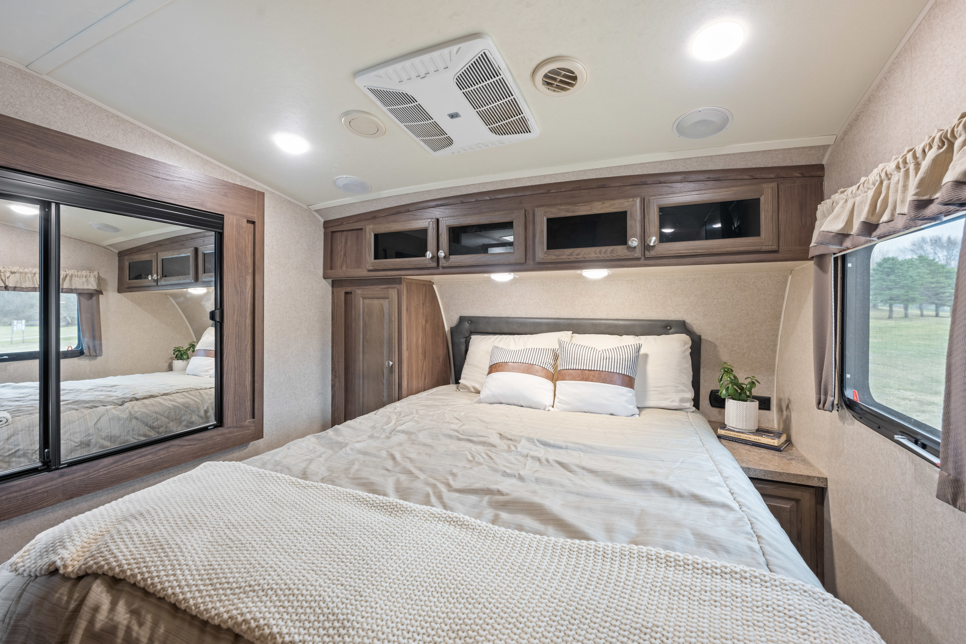 Comfortable RV rental bedroom with a cozy bed, overhead storage, mirror, and window view.. Forest River Signiture Ultra Lite 2017