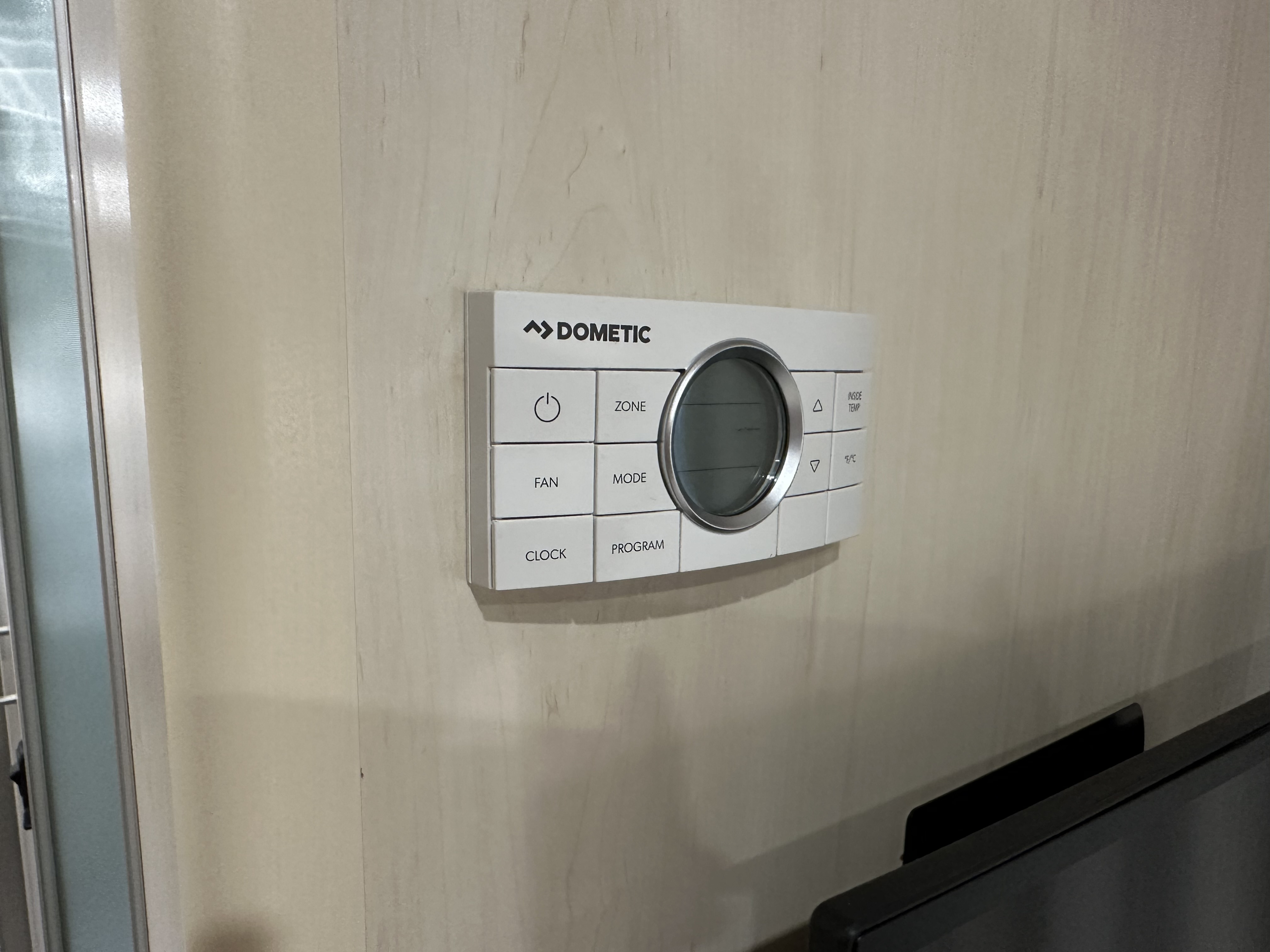 White Dometic climate control thermostat in an RV rental, mounted on a light wood wall.. Airstream Flying Cloud 2023