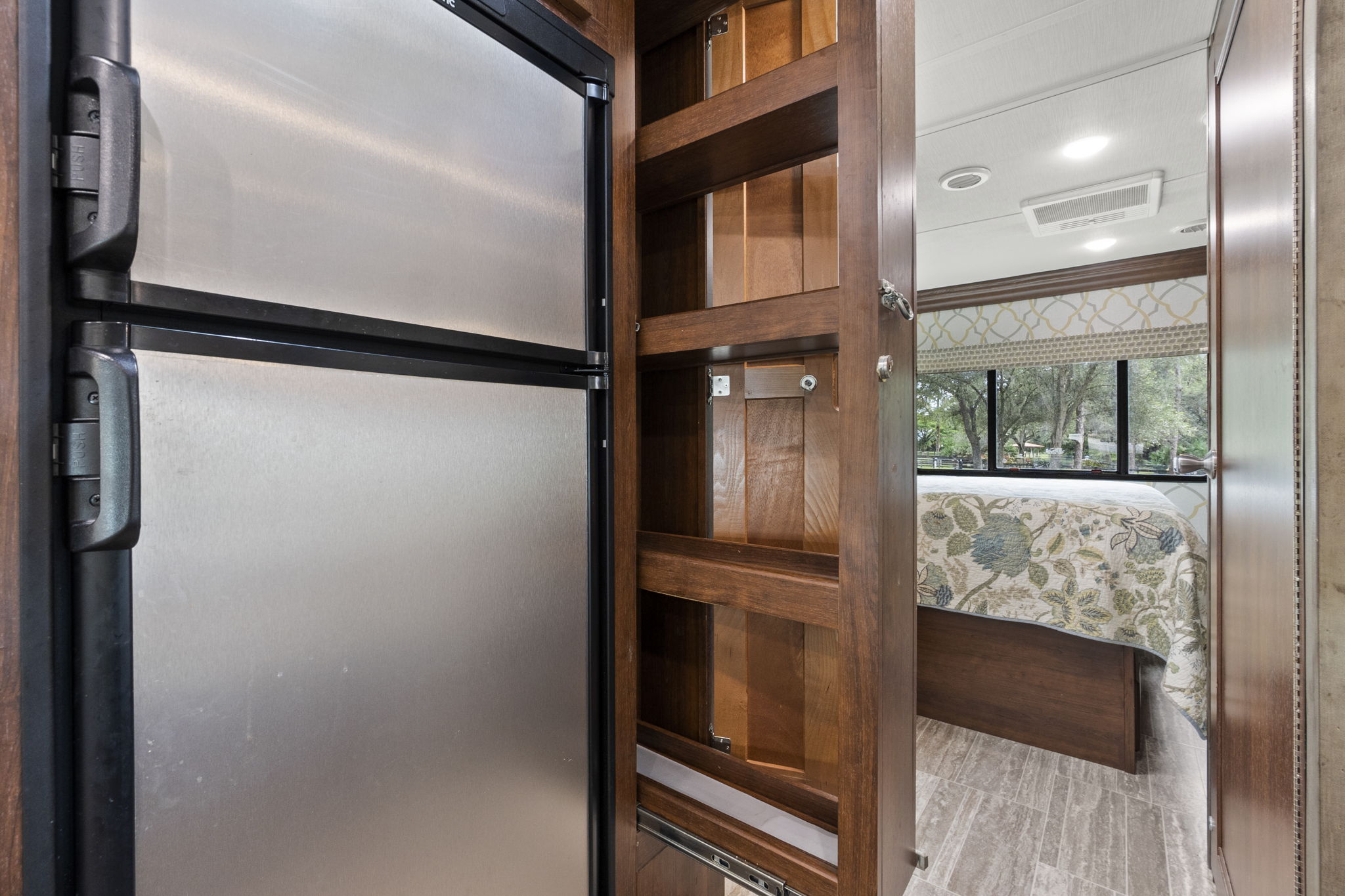 RV rental: Modern RV interior with a stainless steel fridge, pull-out pantry, and a bedroom featuring a patterned bed.. Forest River Sunseeker Classic 2021