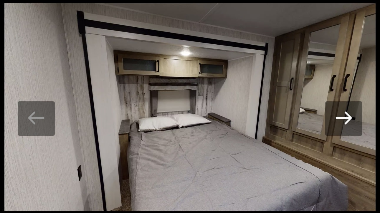 RV rental bedroom with a full bed, overhead storage, mirrored wardrobe, and rustic wall details for comfortable travel.. Forest River Palomino Puma 2022