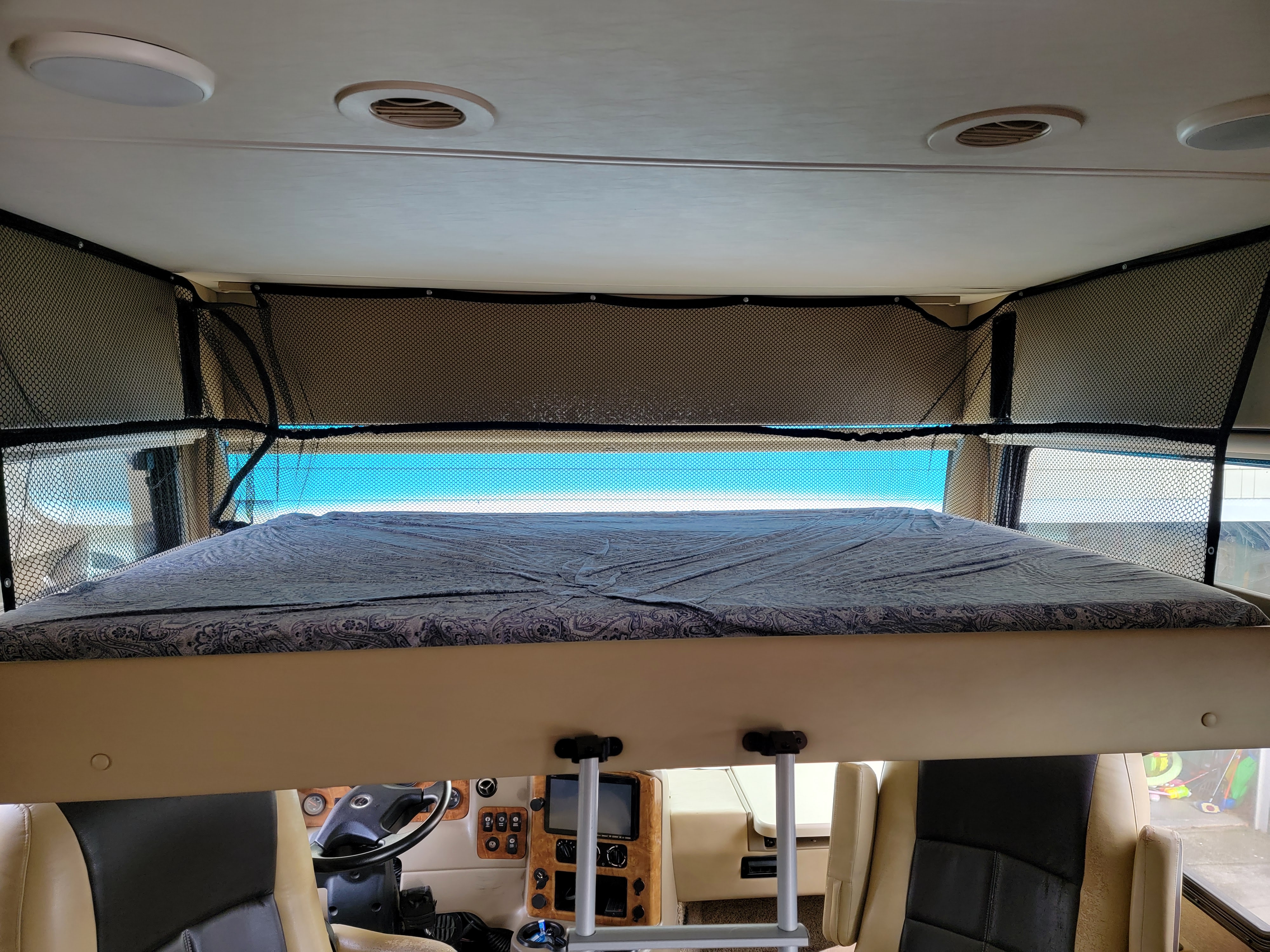 Inside an RV rental: view of the front overhead bunk with safety net, above the driver's area and dashboard.. Thor Palazzo 2016