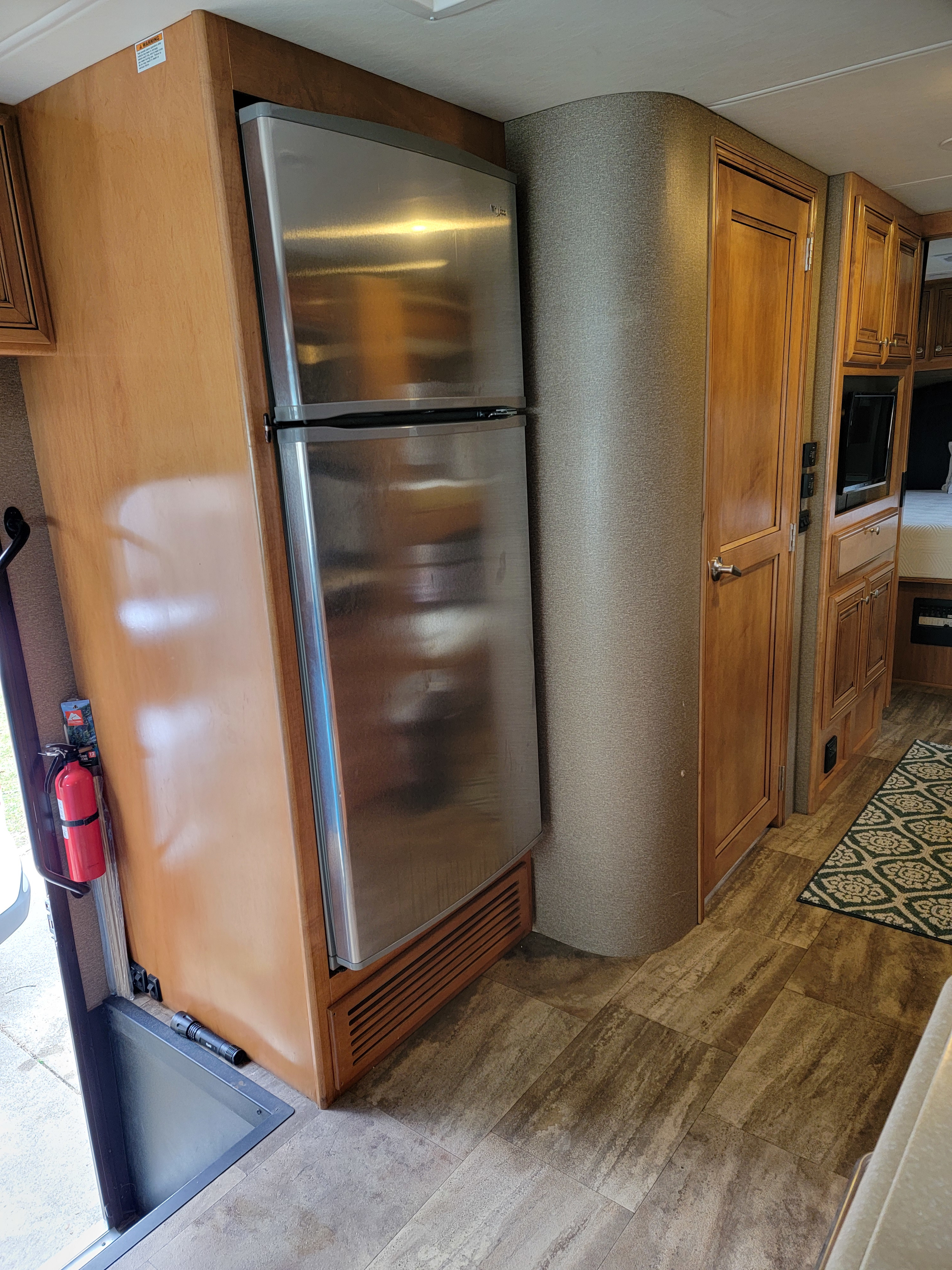 Inside an RV rental: full-size stainless steel refrigerator, wooden cabinets, and a peek into the bedroom.. Thor Palazzo 2016