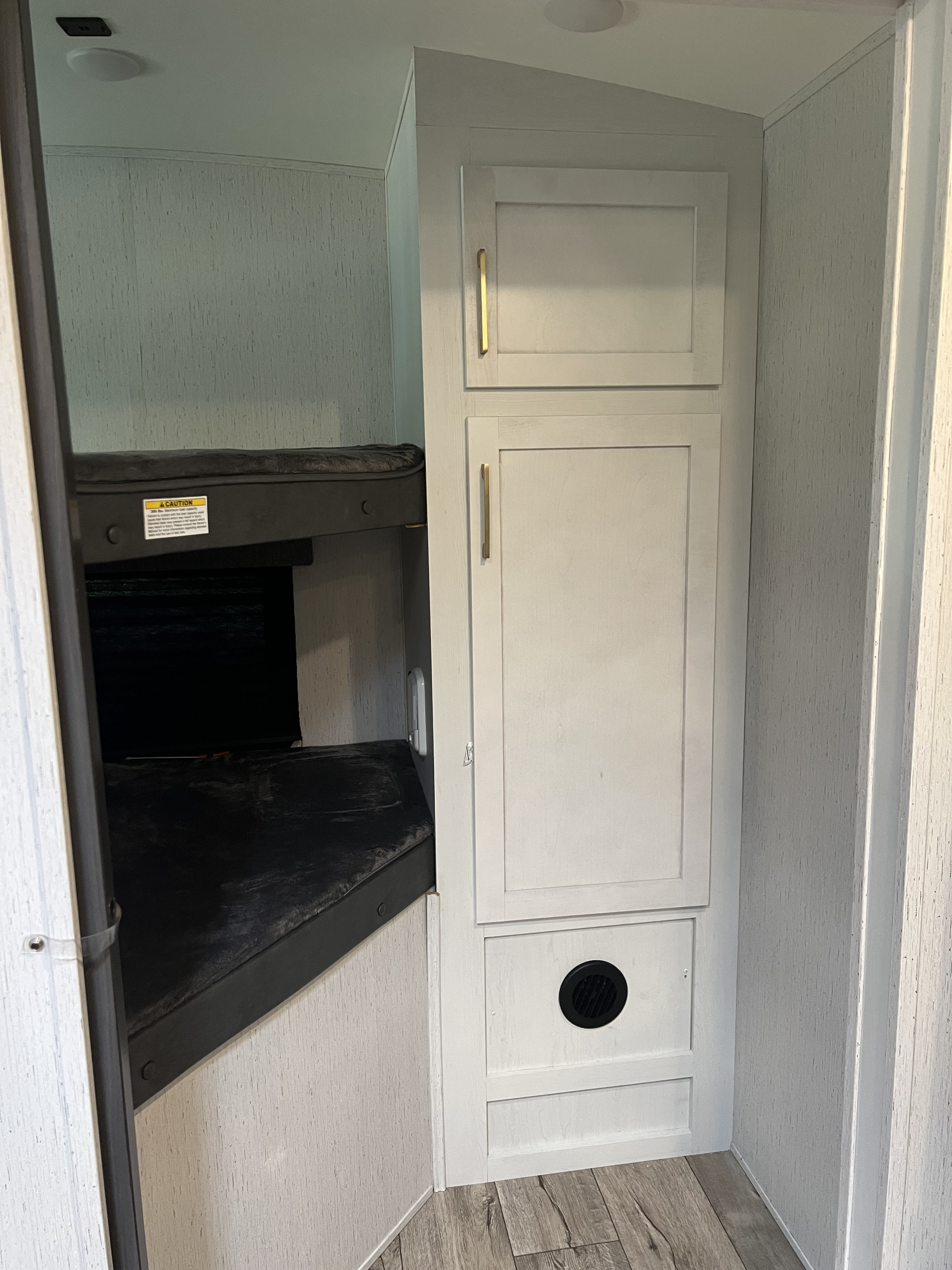 Inside an RV rental: light gray cabinets with gold pulls, bunk beds, and a vent. Perfect for family travel.. Keystone RV Astoria 2903BH 2022