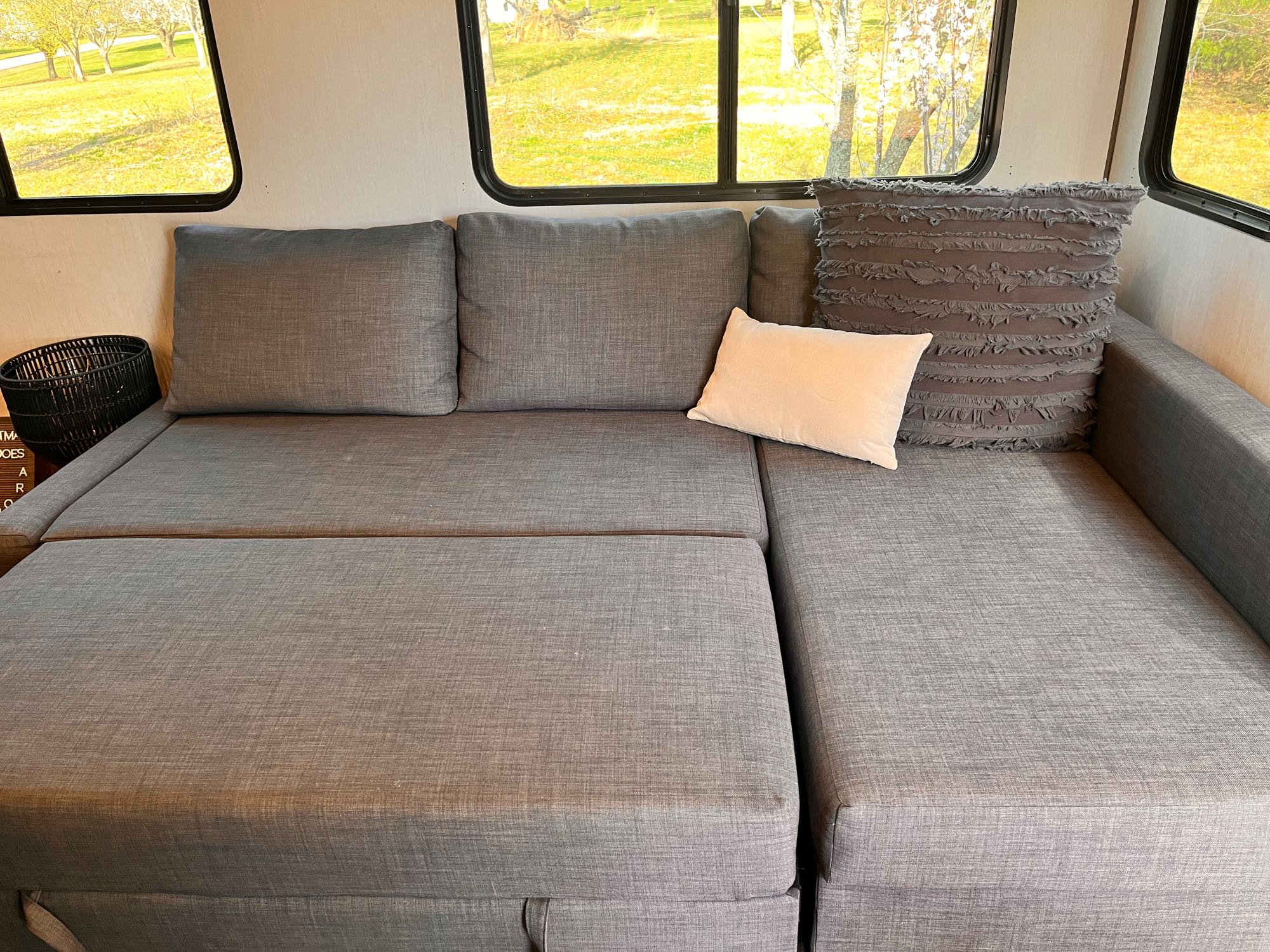 Cozy gray sectional couch in an RV rental, offering comfortable lounging with scenic outdoor views through large windows.. Forest River Sabre 2022