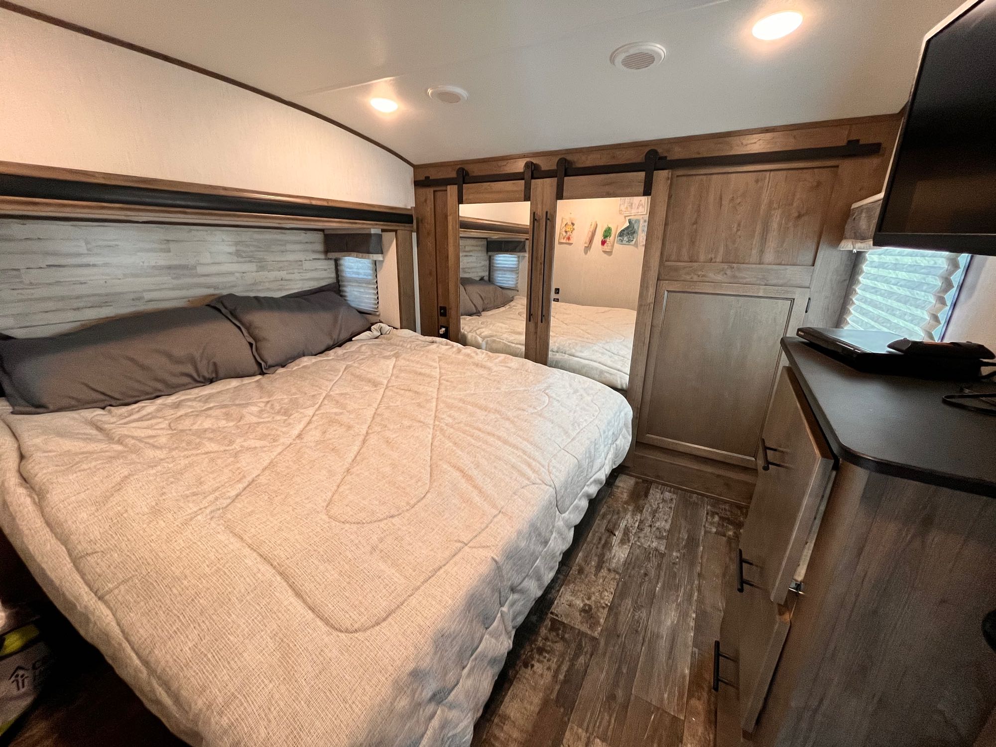 Cozy RV rental bedroom featuring a comfortable bed, mirrored closet, storage, and TV for a relaxing journey.. Forest River Sabre 2022
