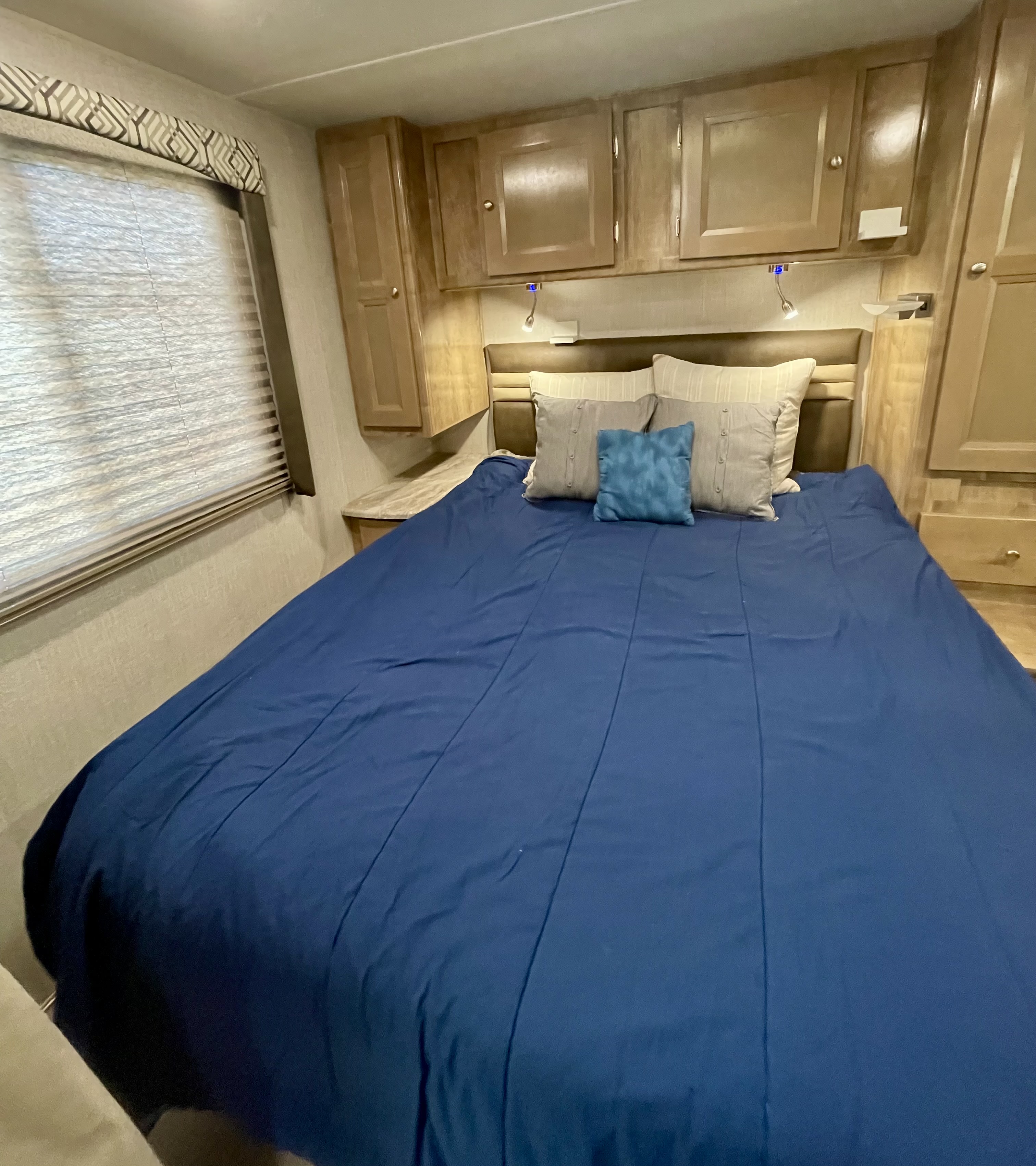 Cozy RV rental bedroom with a comfy bed, overhead storage, and window shades, perfect for your next trip.. Forest River Coachmen Leprechaun 2020