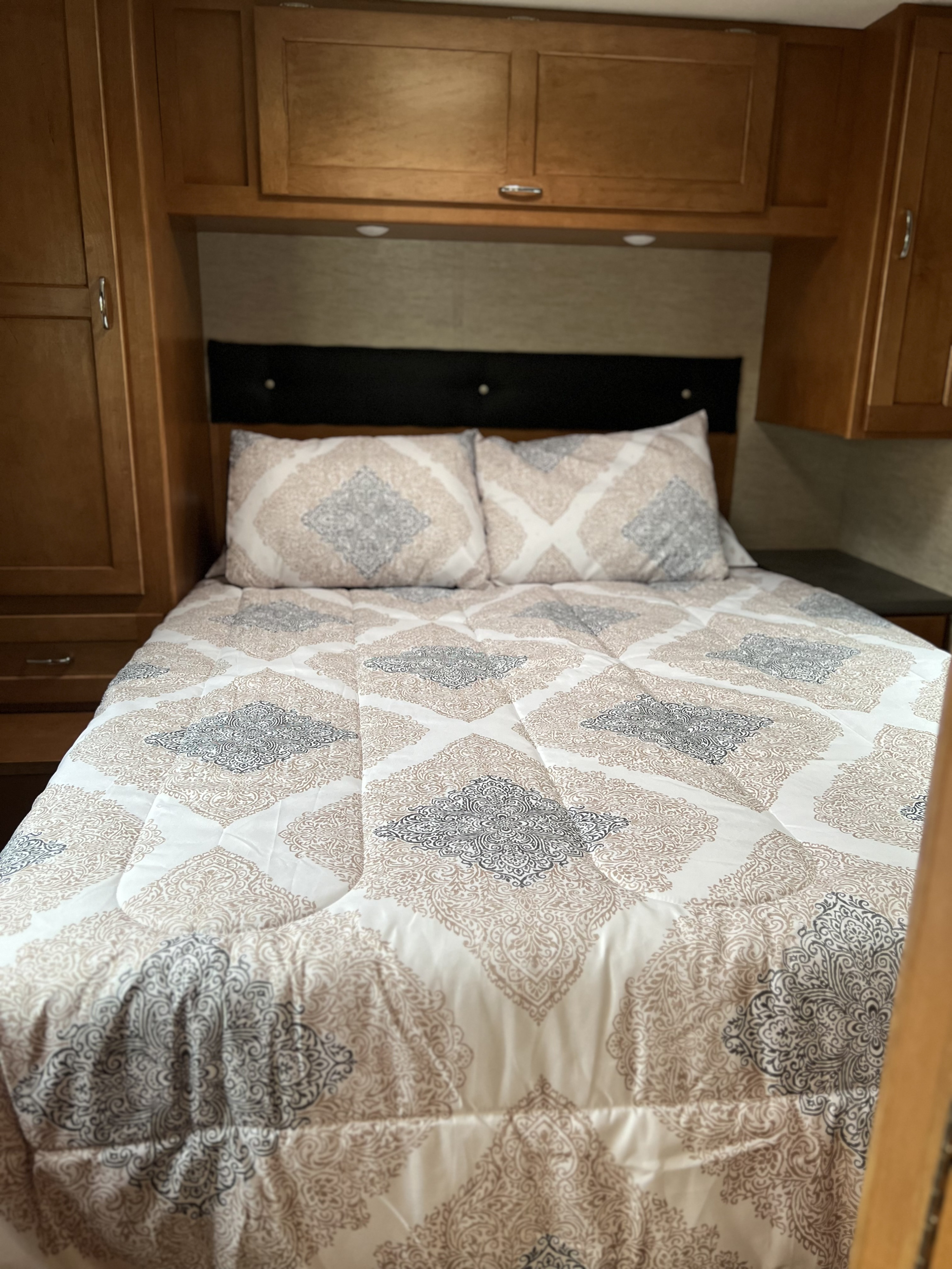 Cozy RV rental bedroom with patterned bedding & overhead storage.. Winnebago Minnie Winnie 2016