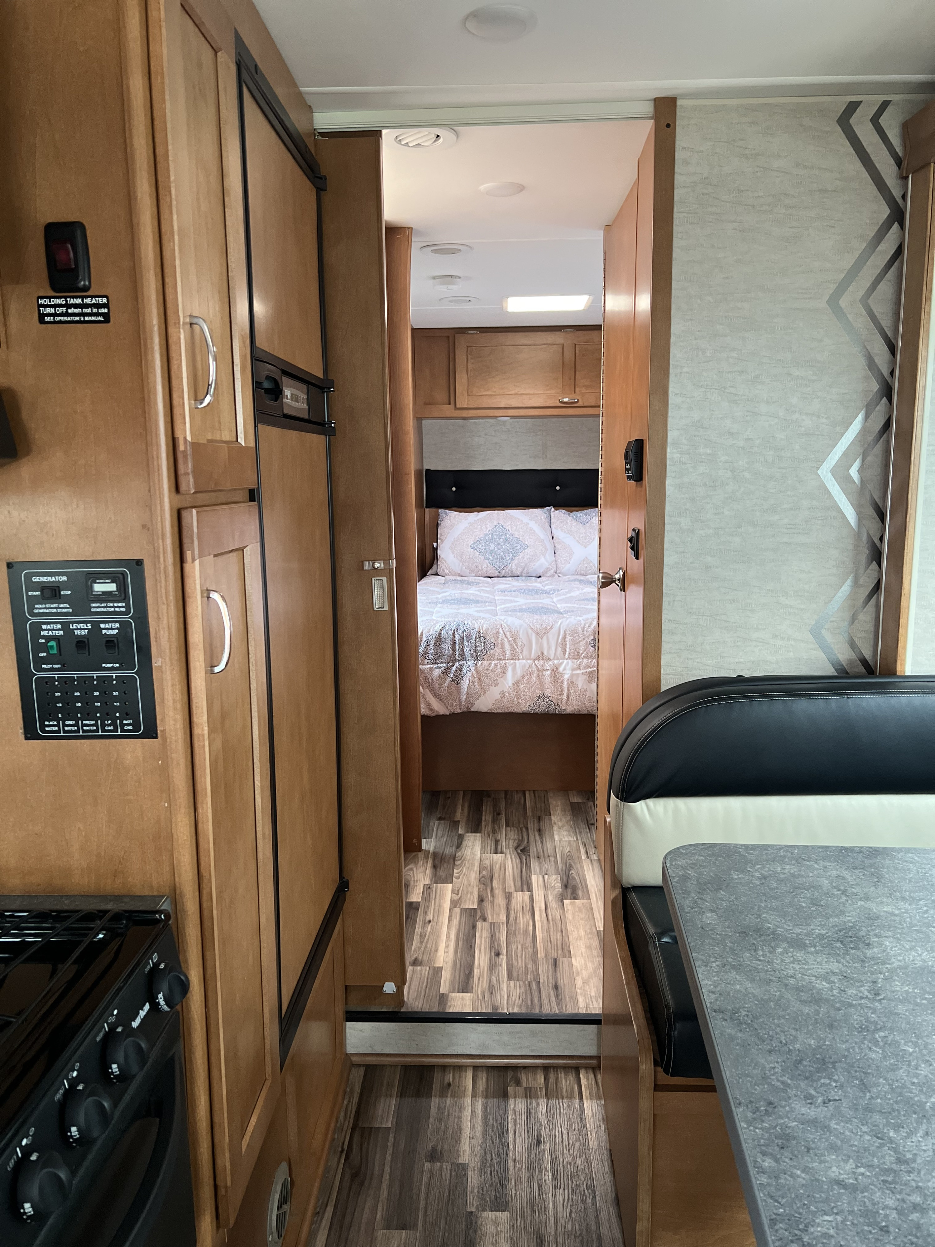 Inside this rv rental, view the main cabin with kitchen controls & appliances, leading to a bedroom, plus a dinette.. Winnebago Minnie Winnie 2016