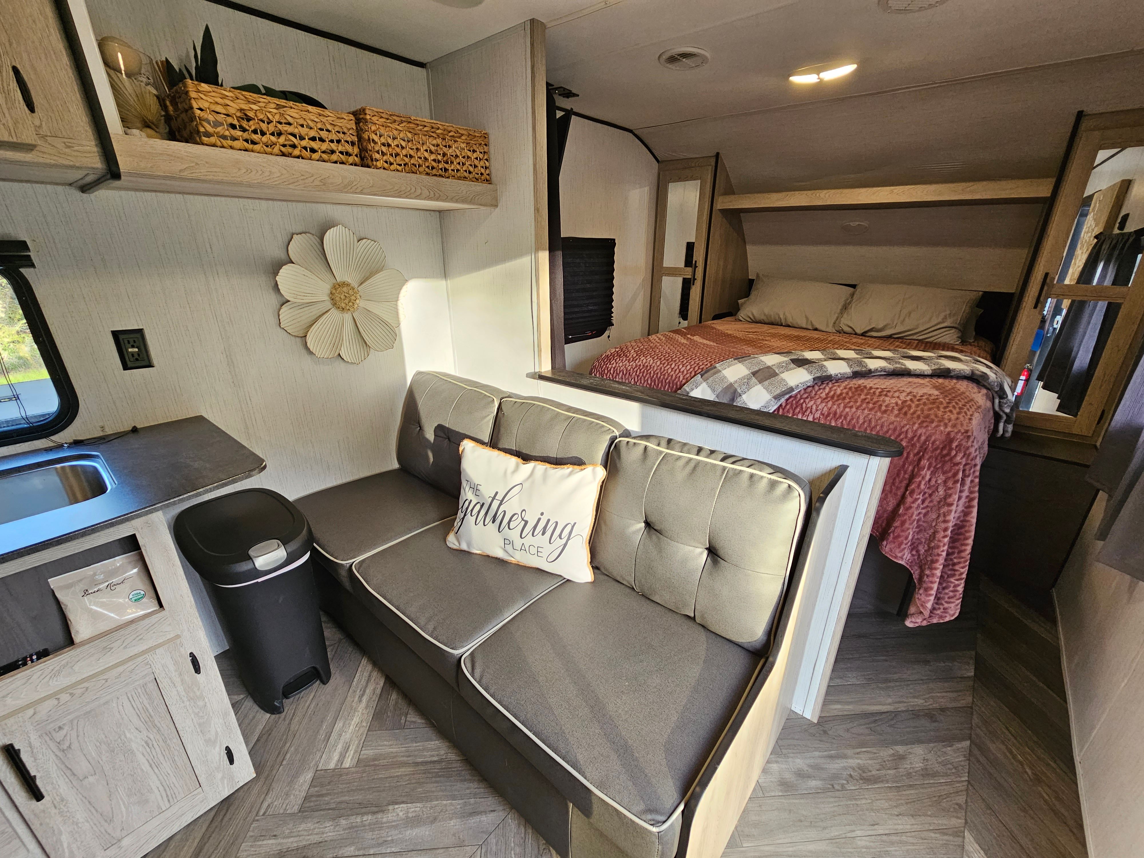 This welcoming RV rental features a cozy bed, plush sofa, and compact kitchen area, designed for comfortable travel and adventures.. Keystone Prowler 2021