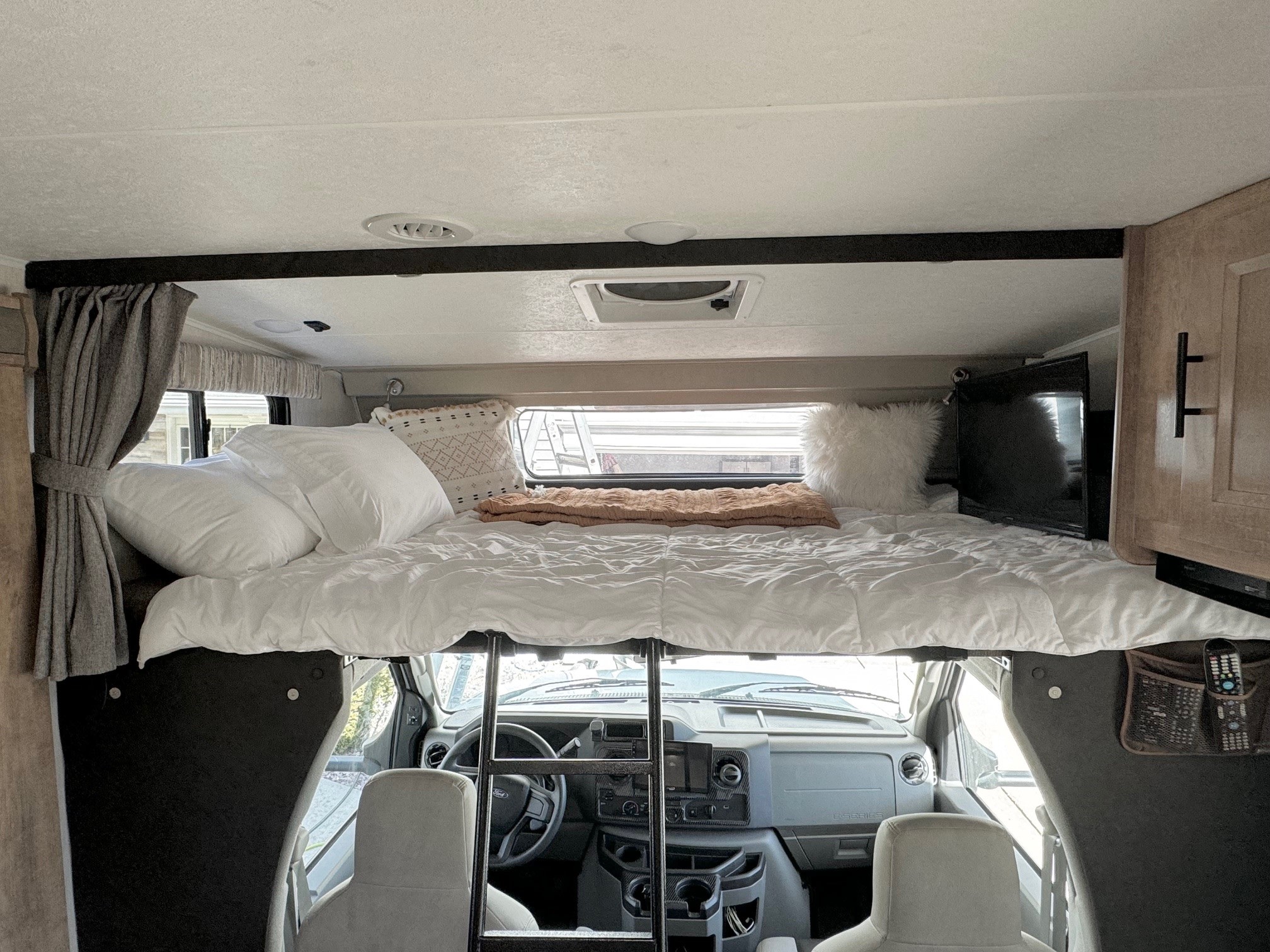 Inside an RV rental, showcasing the comfy over-cab bunk bed and front cockpit. Ideal for your next road trip.. Forest River Coachmen Leprechaun Premier 2021