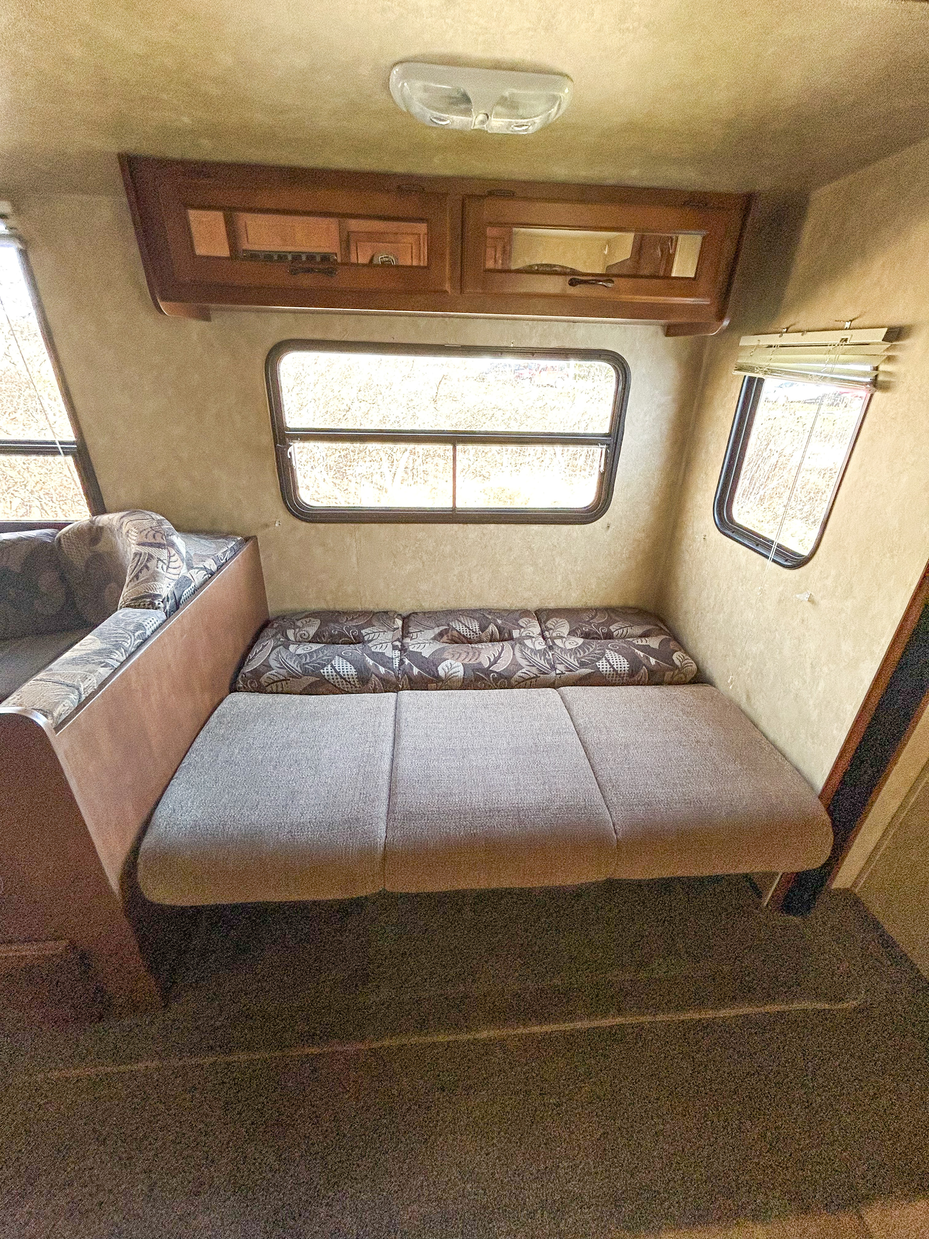 Cozy RV rental interior featuring convertible seating/bed, overhead cabinets, and large windows. Perfect for your next adventure!. Coachmen Catalina 2013