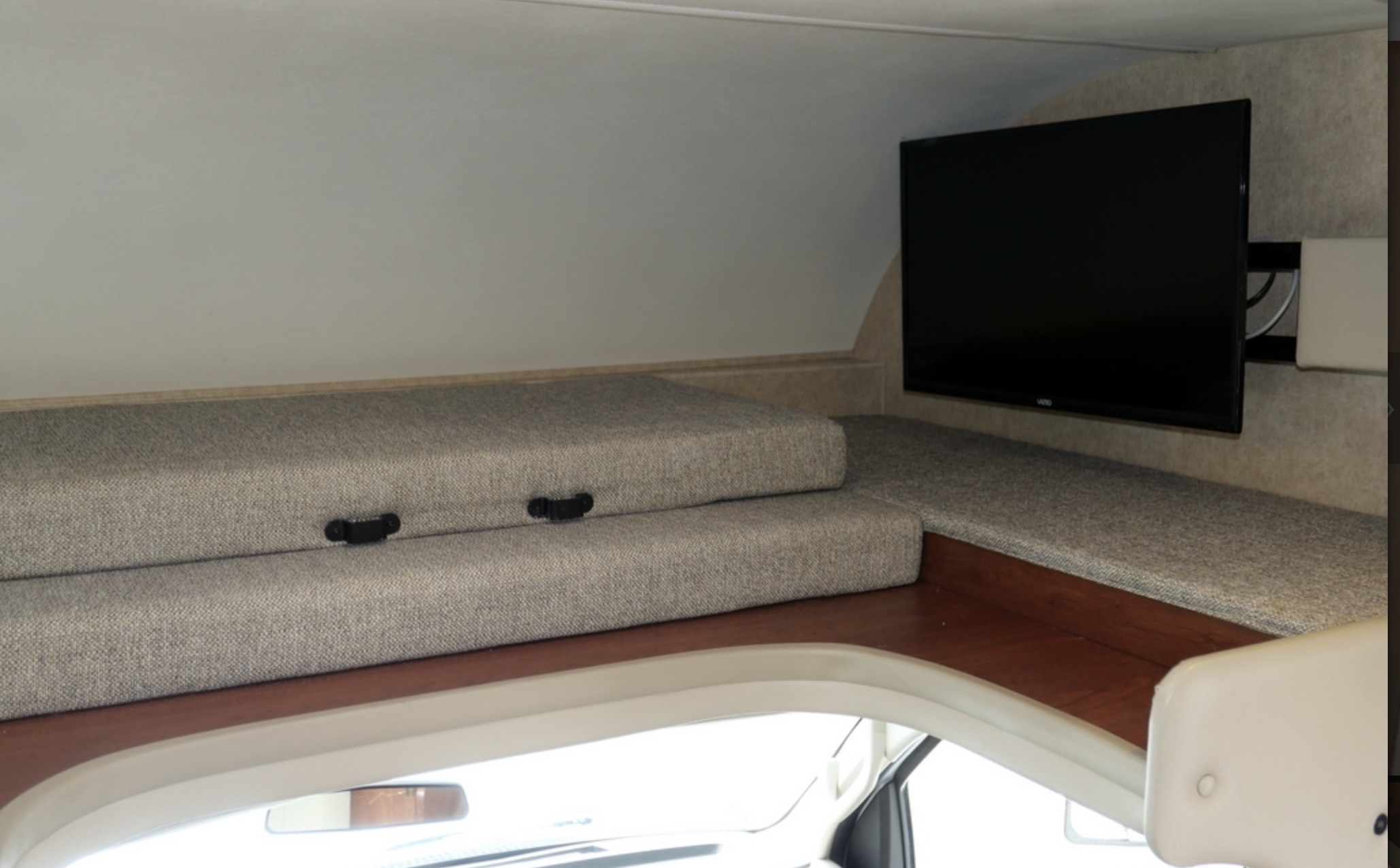 RV rental interior: cozy cab-over bunk bed with gray cushions and a mounted flat-screen TV.. Thor Freedom Elite 2017