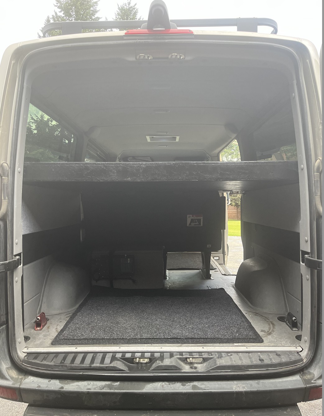 RV rental van interior showing spacious cargo area beneath a raised bed platform. Ideal for gear storage.. Mercedes-Benz Sprinter 2018