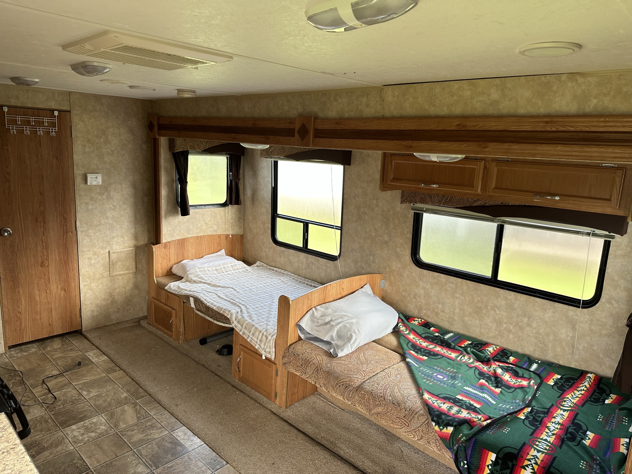 Inside an RV rental: a cozy sleeping/lounge area with two upholstered benches, bright windows, and wood-toned cabinetry.. Jayco Jay Flight 2009