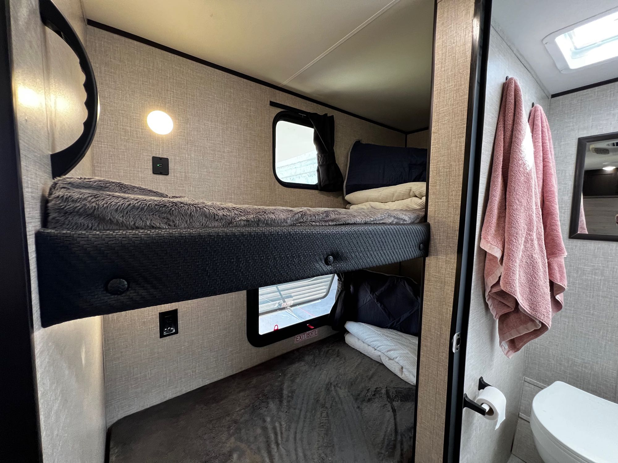 Modern RV rental interior: comfortable bunk beds with personal lighting, USB chargers, and windows, plus a connected bathroom.. Jayco Jay Flight SLX Baja Edition 2023