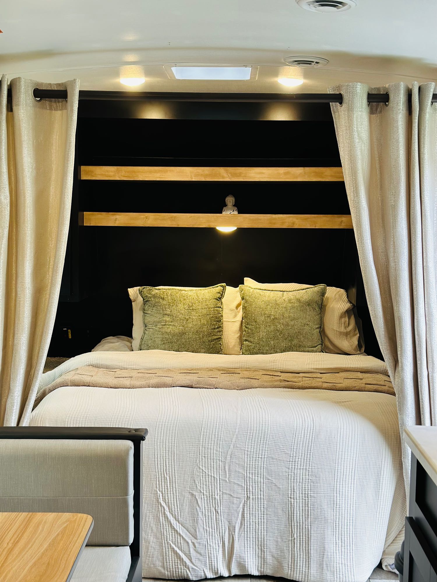 Cozy RV rental bedroom with olive green pillows, soft bedding, modern shelves, and ambient lighting for comfortable travel.. Keystone RV Springdale 2023