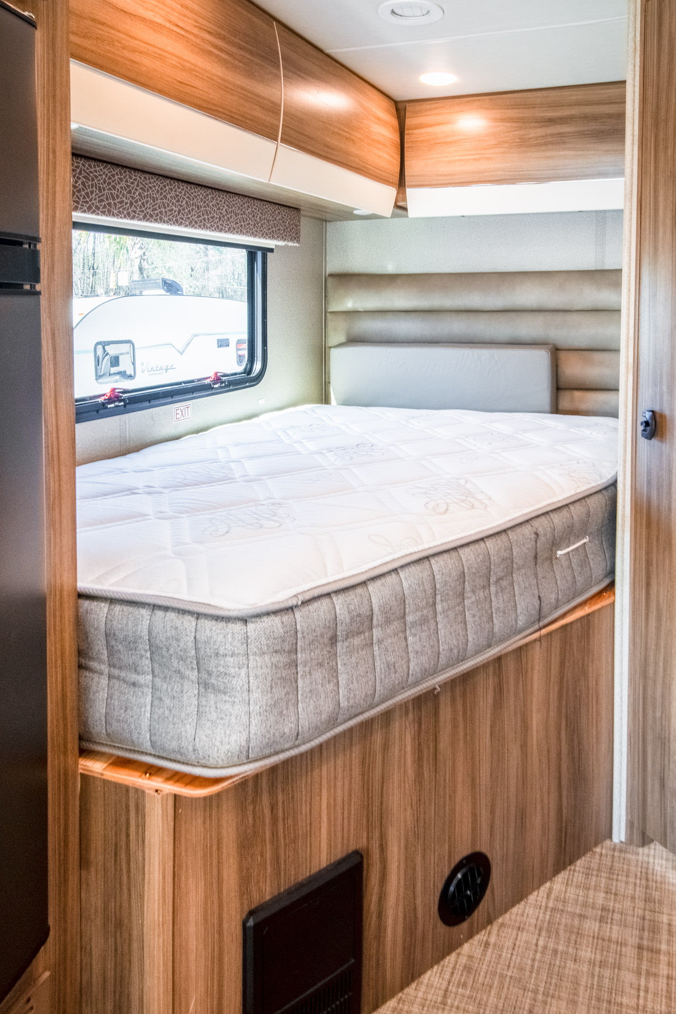 Spacious RV rental bedroom: light wood cabinets, quilted white mattress on a grey base, and a window.. Jayco Melbourne 2019