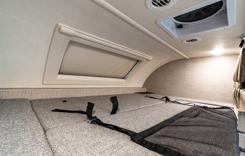 RV rental overhead bunk featuring a comfortable bed, window, safety net, and ceiling vents for comfort.. Thor Motor Coach Qantum 2021