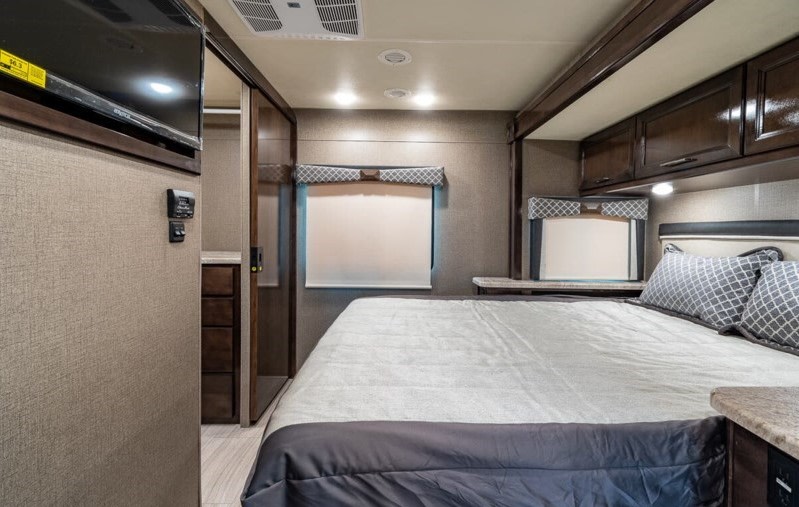 Spacious RV rental bedroom with comfortable queen bed, overhead storage, TV, and closet. Ideal for your next adventure.. Thor Motor Coach Qantum 2021