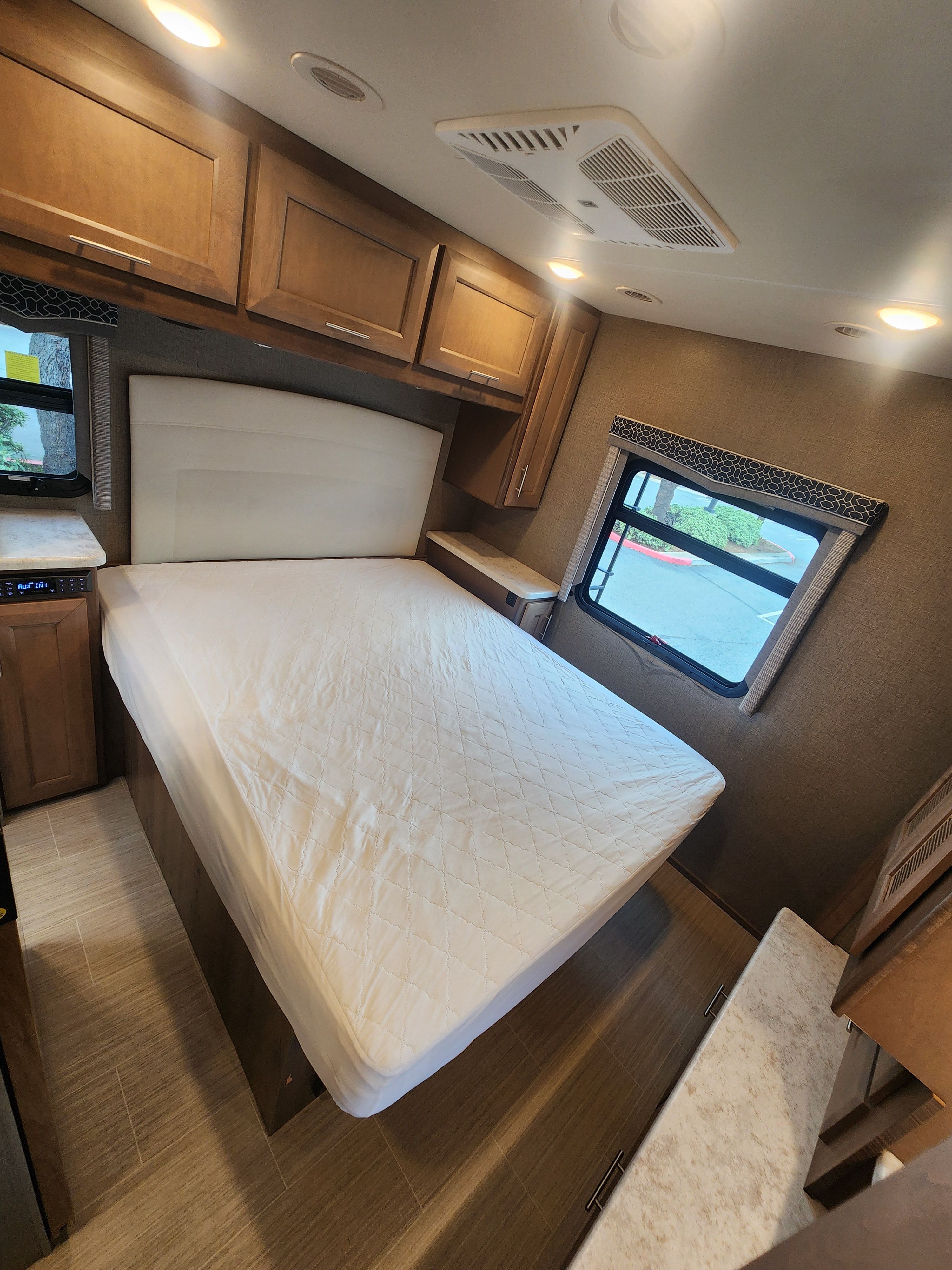 RV rental bedroom: Enjoy the queen bed with padded headboard, wood cabinets, nightstands, and window views.. Thor Motor Coach Magnitude 2021