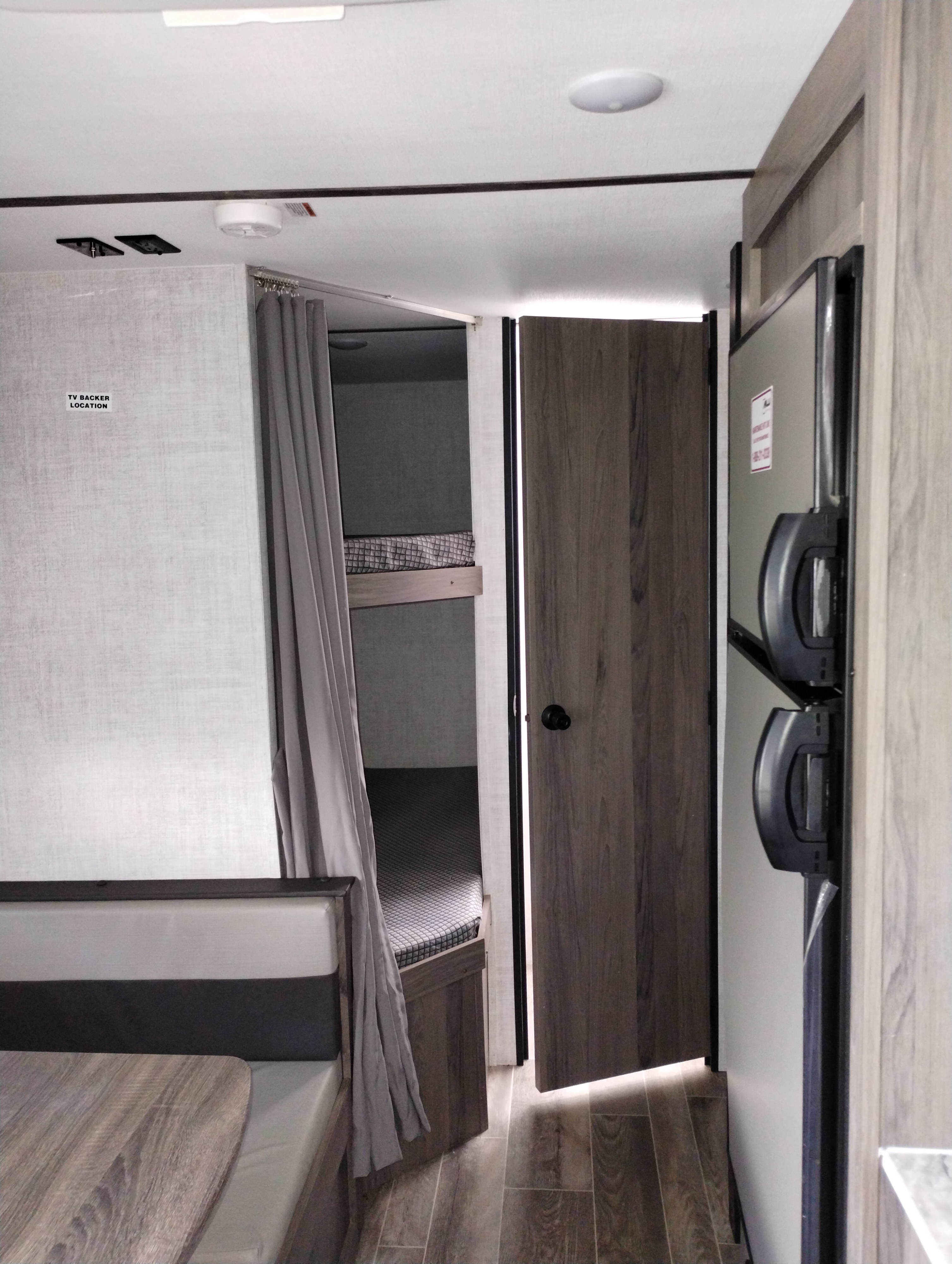 RV rental interior featuring a cozy dinette, bunk beds, and a refrigerator, offering comfort on the go.. Gulf Stream Ameri-Lite 2022
