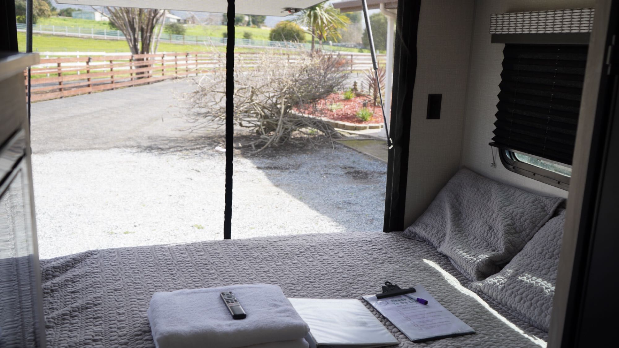 Cozy RV rental bedroom with a comfortable bed, fresh towels, and a tranquil view of the fenced outdoors.. KZ Escape Hatch 2021