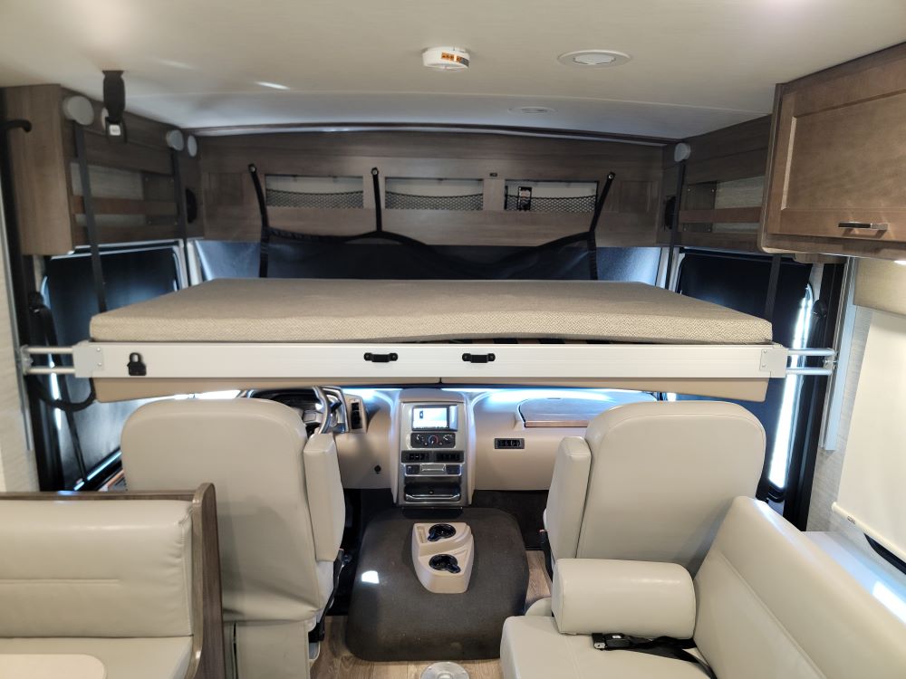 Spacious RV rental interior with a drop-down bunk bed over the cab seats, offering extra sleeping space in this motorhome.. Winnebago Sunstar 2022