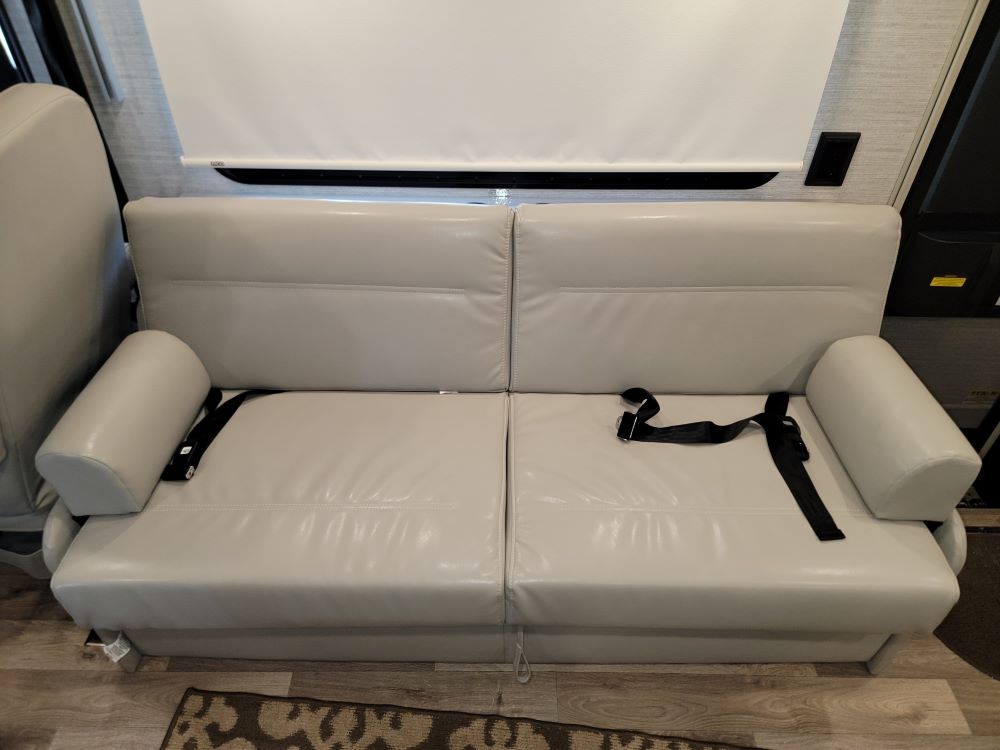 Spacious RV rental sofa in light upholstery, featuring integrated seatbelts for safe travel. Ideal RV seating.. Winnebago Sunstar 2022