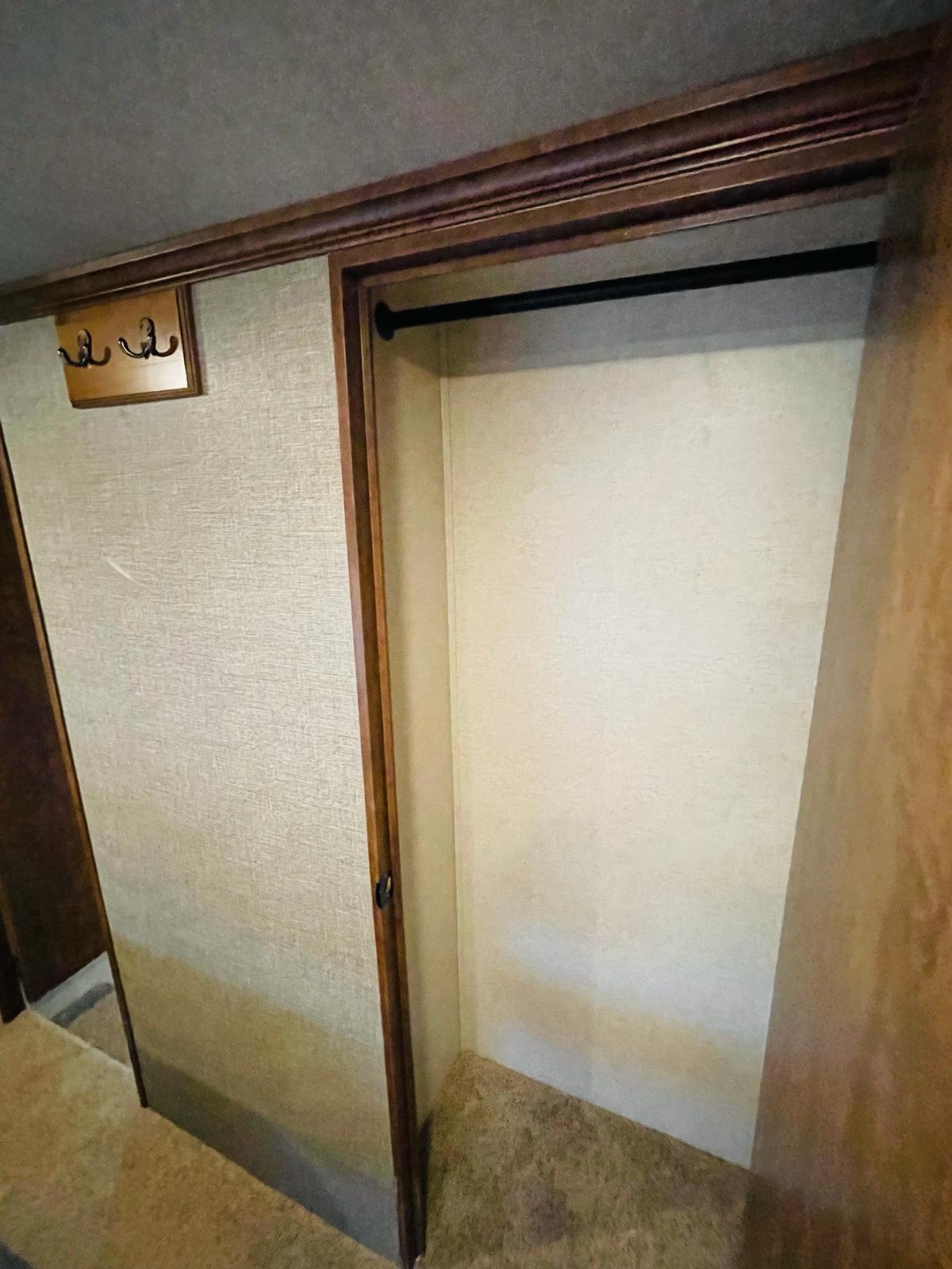 RV rental closet with a hanging rod and wall hooks, offering practical wardrobe storage in a compact interior.. Heartland RVs Big Country 2016