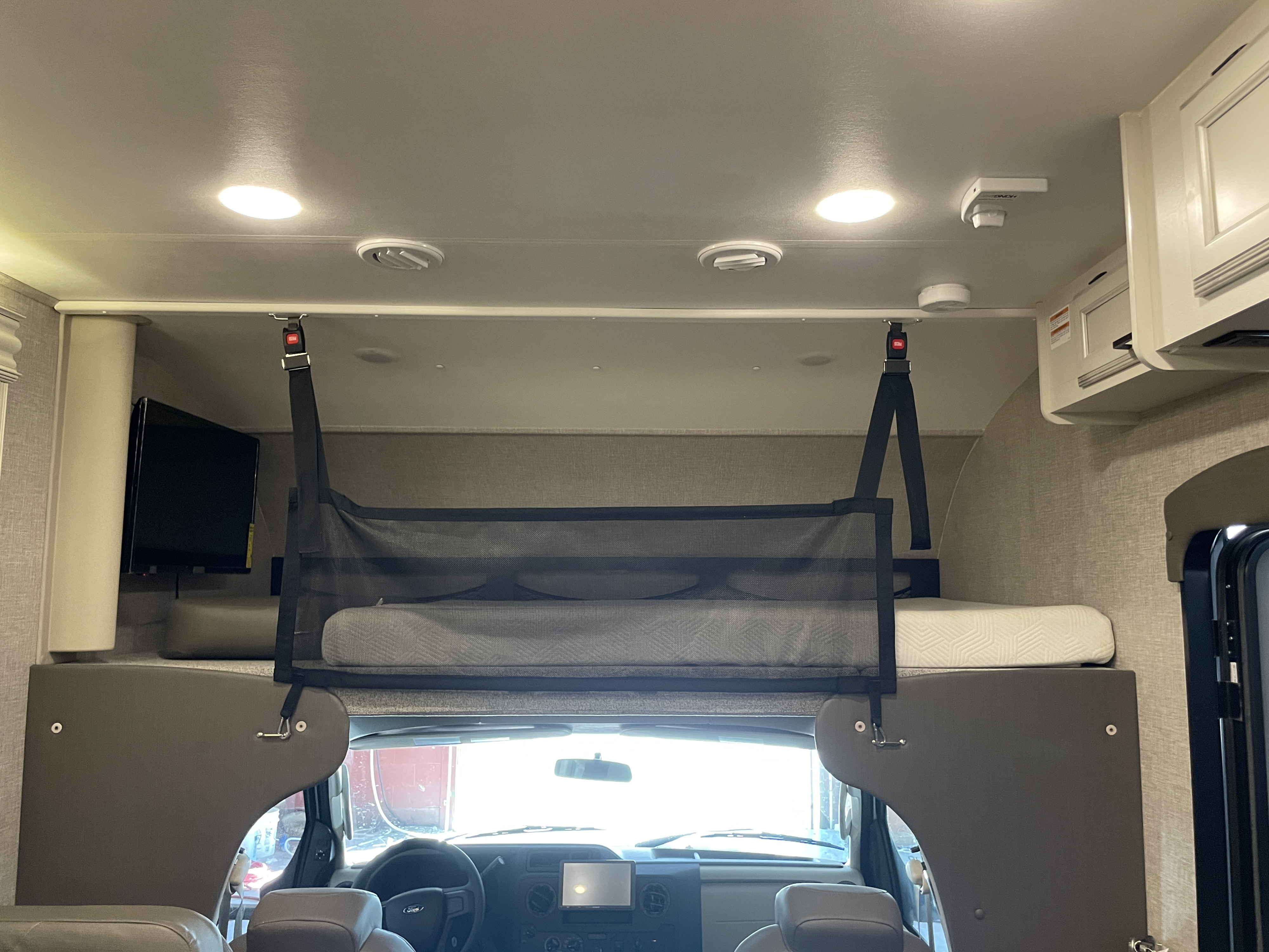 Interior of an RV rental showing the overhead bunk bed with a safety net, ideal for extra sleeping space.. Jayco Redhawk 2022