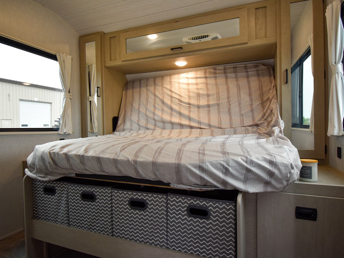 Cozy RV rental bedroom featuring a comfortable bed with striped bedding, convenient under-bed storage, and bright windows.. Forest River Salem 2024