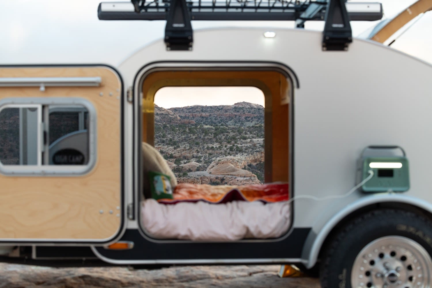 RV rental comfort: A teardrop trailer's open door reveals a cozy bed & stunning desert vista, powered for off-grid adventures.. Tear Drop Tear Drop 2019