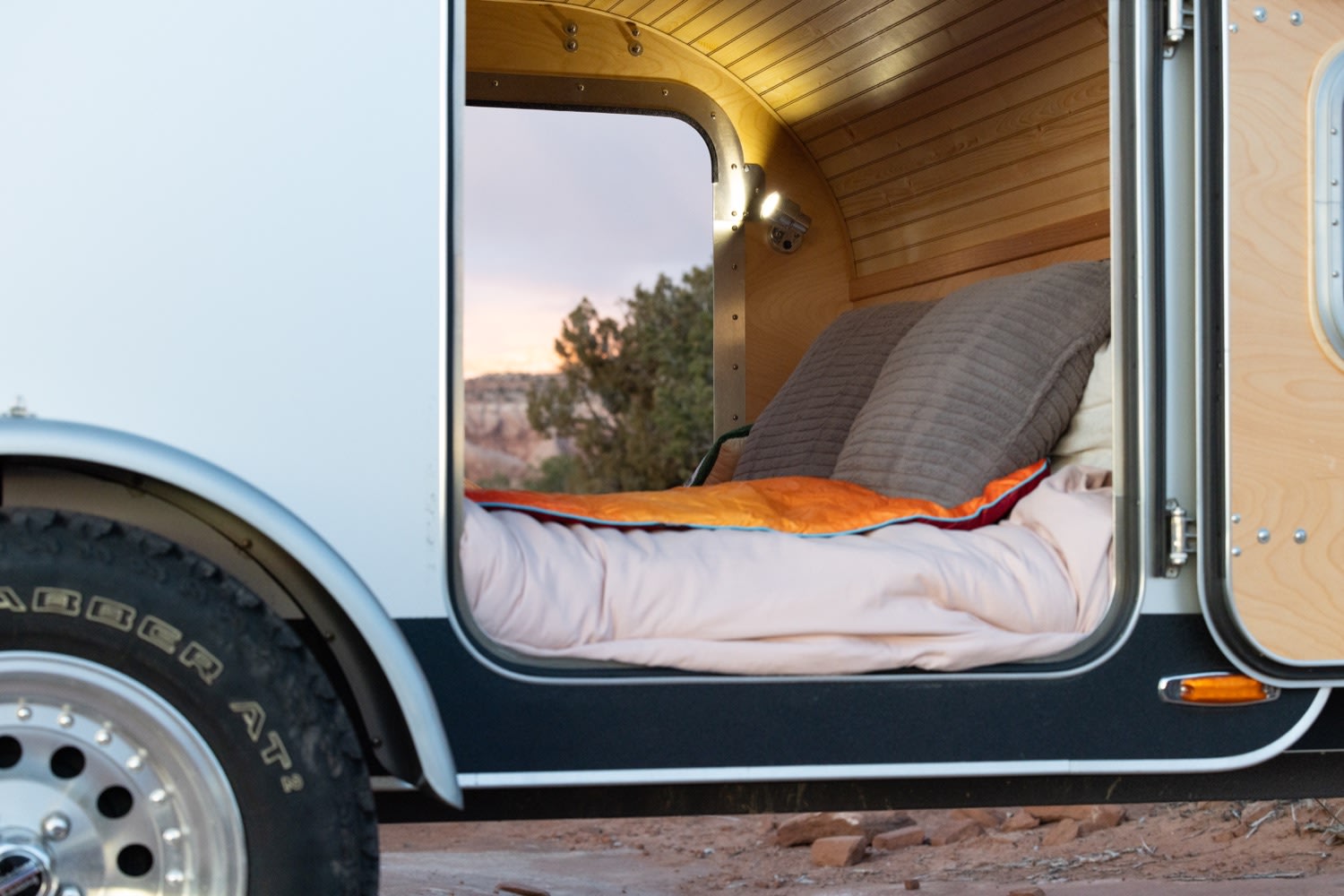 Cozy rv rental bed with wood interior, offering comfort & a scenic sunset view from inside the camper.. Tear Drop Tear Drop 2019