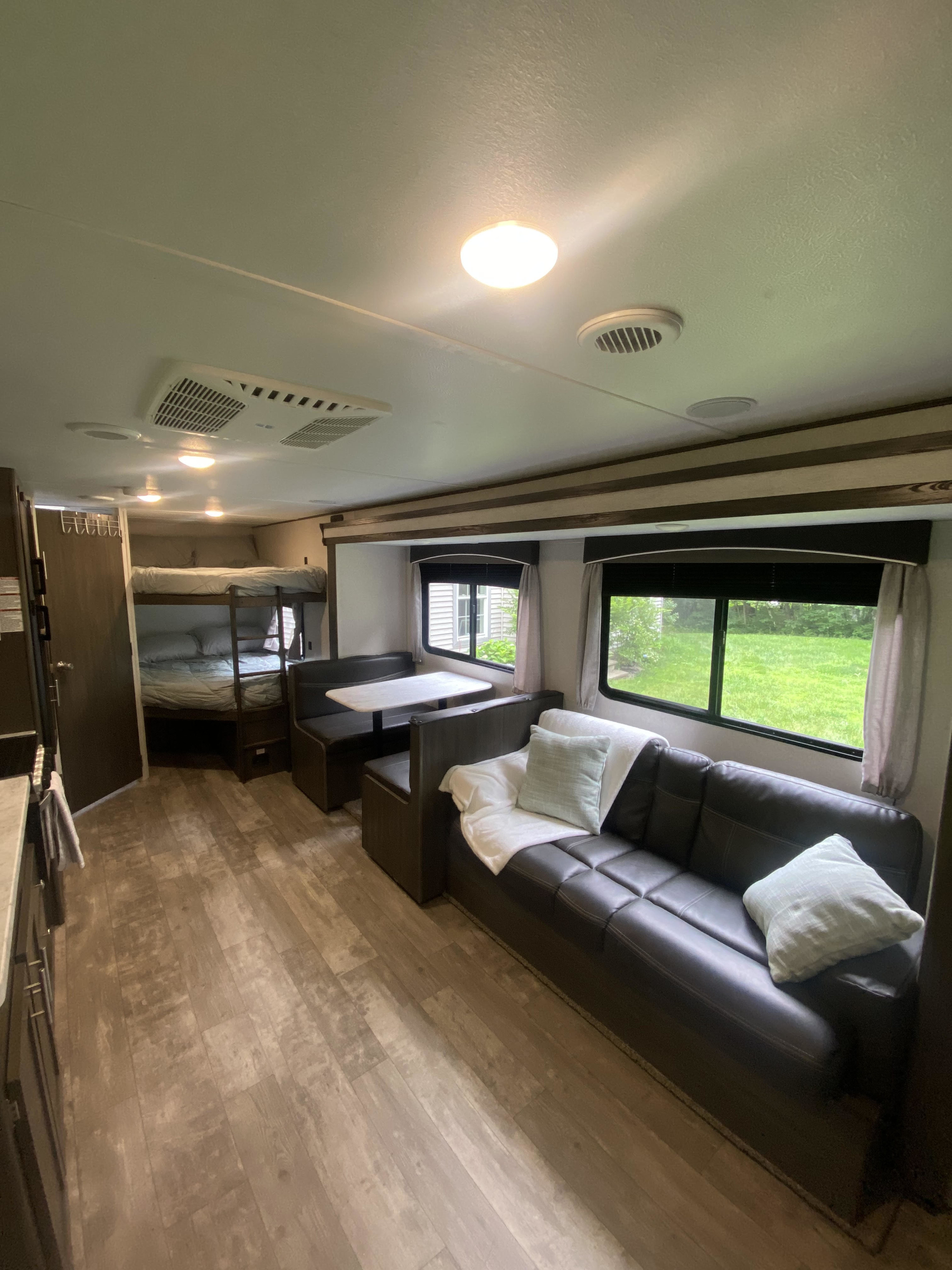 Bright RV rental interior with comfortable sofa, dinette, and cozy bunk beds. Ideal for travel.. Forest River Shasta 2021