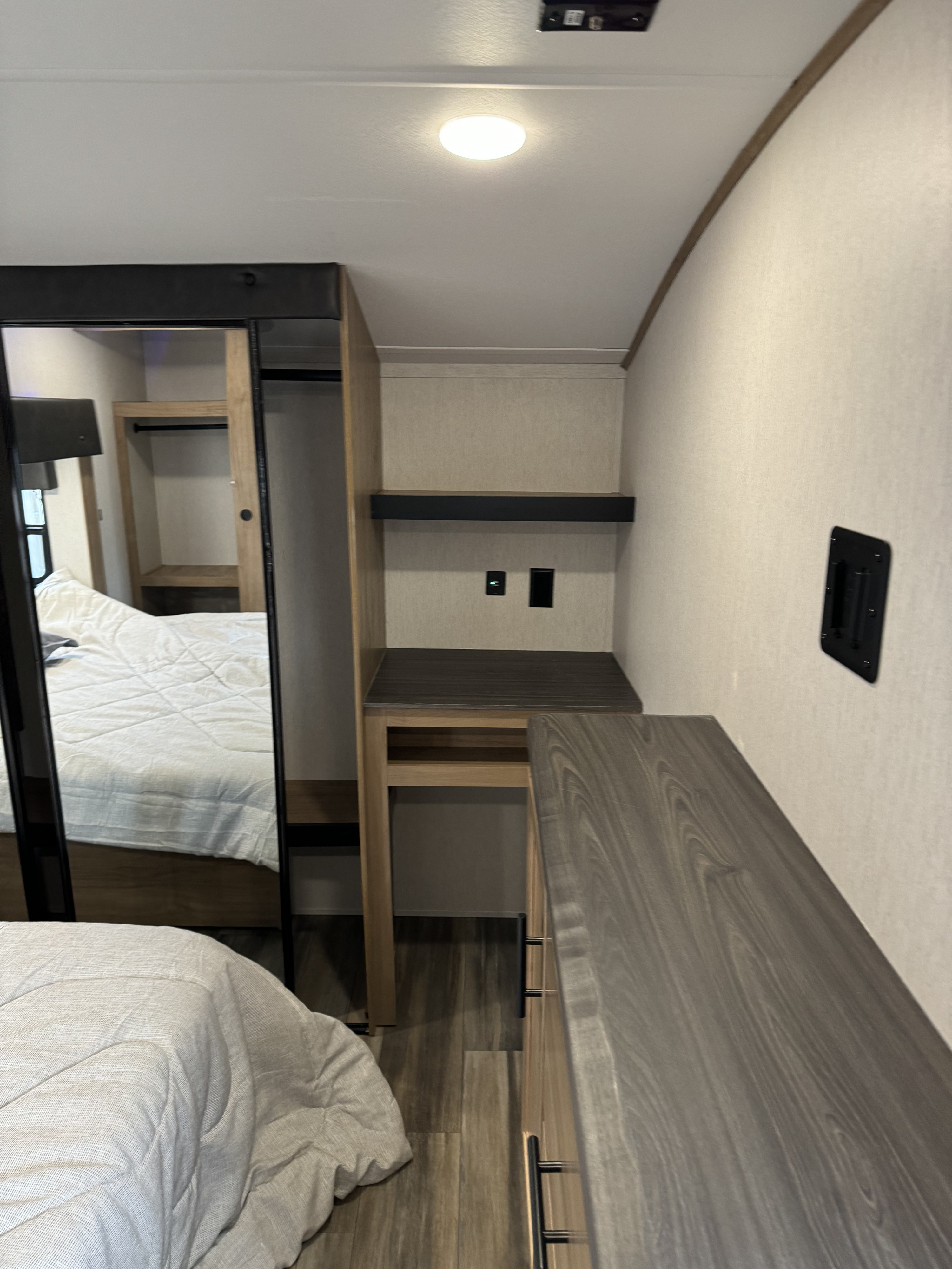 RV rental bedroom interior featuring a bed, mirrored closet, storage area, and wall mount.. Forest River Cherokee Arctic Wolf 2023