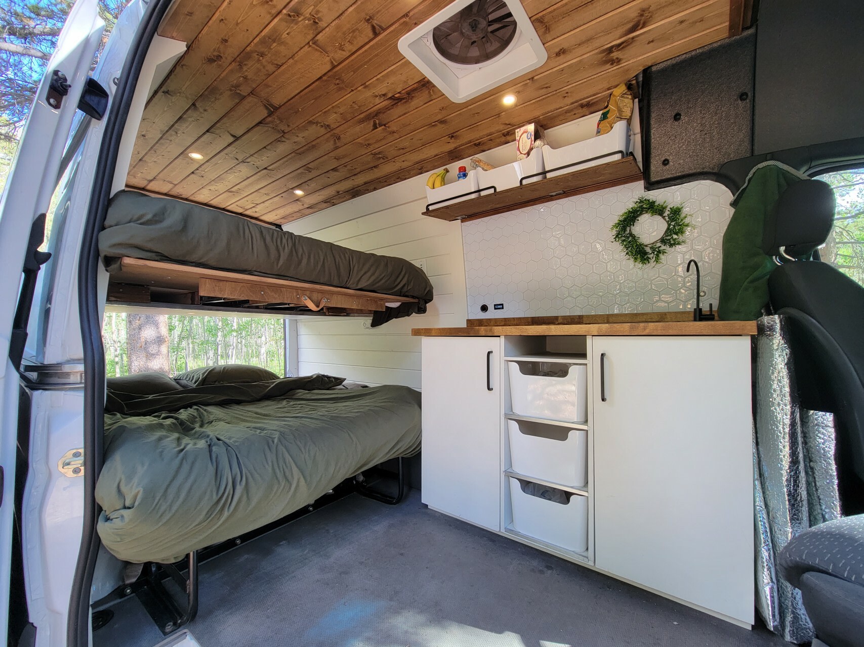 Comfy rv rental van interior: wooden ceiling, upper & lower beds, plus a compact kitchen with wood counters & tiled backsplash.. Mercedes-Benz Sprinter 2020