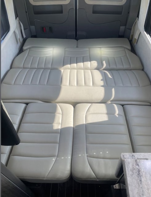 RV rental interior showing beige upholstered seating convertible to a bed in the rear of the vehicle.. Airstream Interstate 2014