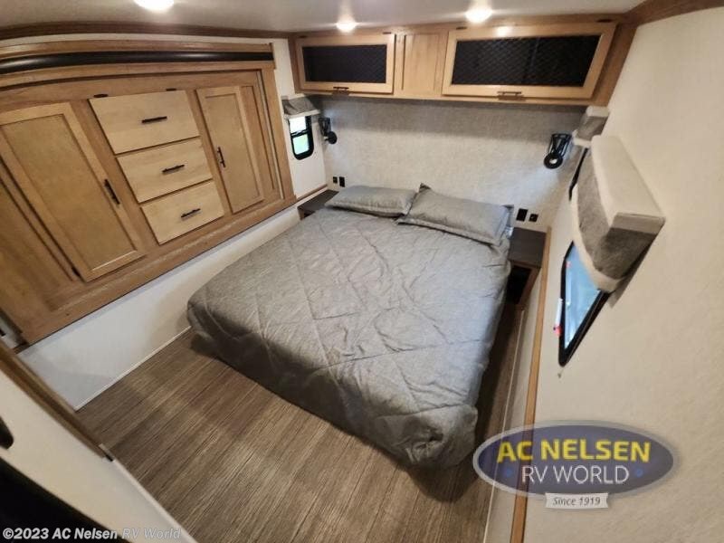 Cozy RV rental bedroom featuring a comfy bed, overhead cabinets, and built-in storage drawers. Ideal compact living.. Forest River Sabre 2023