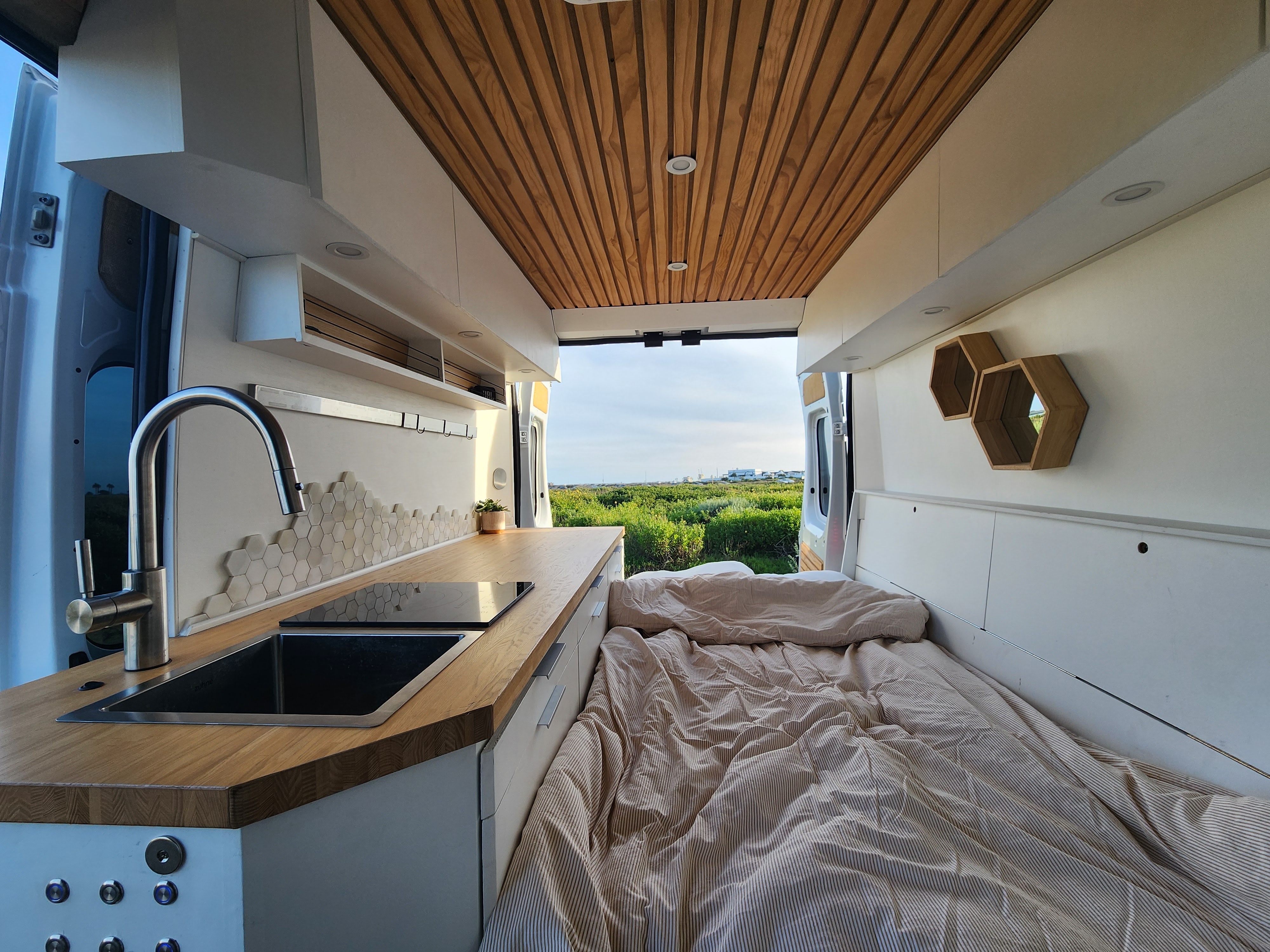 Spacious RV rental interior with modern kitchen, comfy bed, and open views. Perfect for adventure travel.. Dodge Sprinter Van 2015
