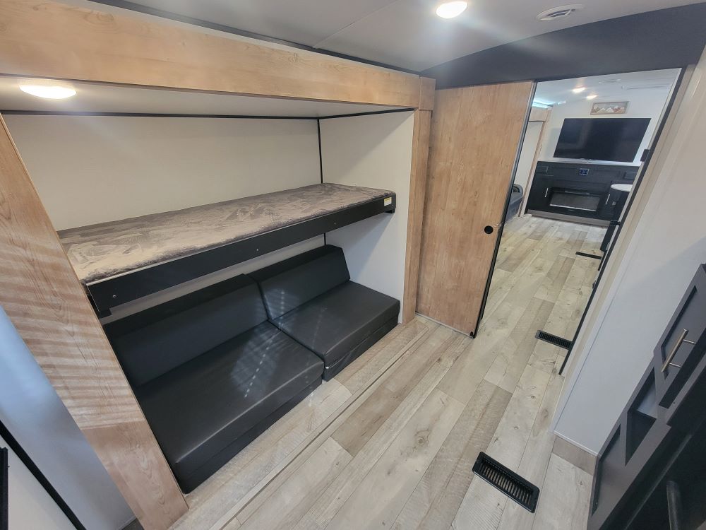 Discover the comfortable interior of this RV rental, featuring practical bunk beds, a convertible sofa, and a cozy living area.. Keystone RV Springdale 2023